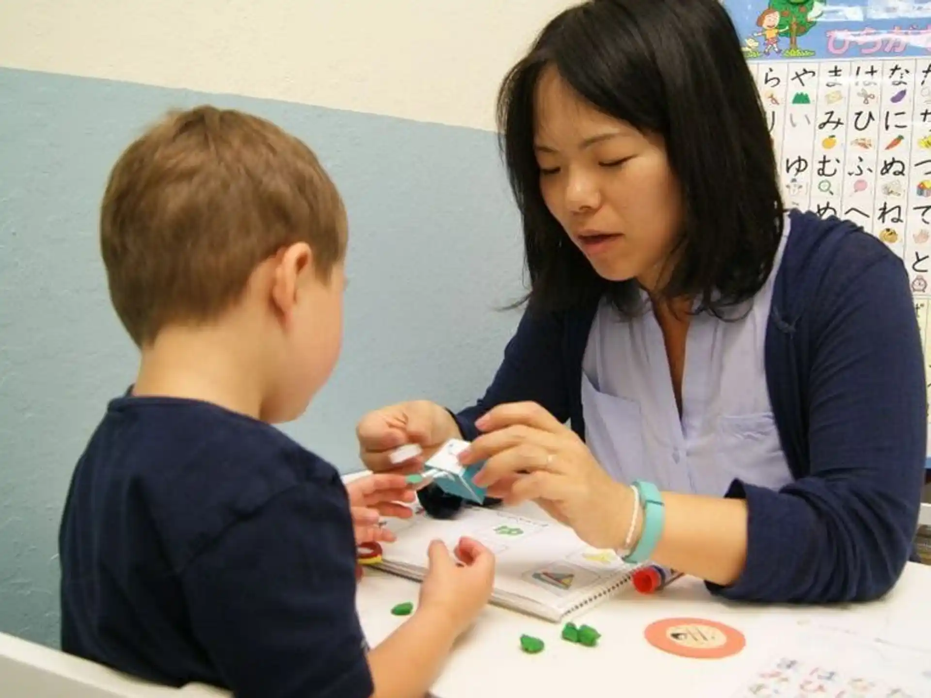 a person and a boy sitting at a table looking at a paper