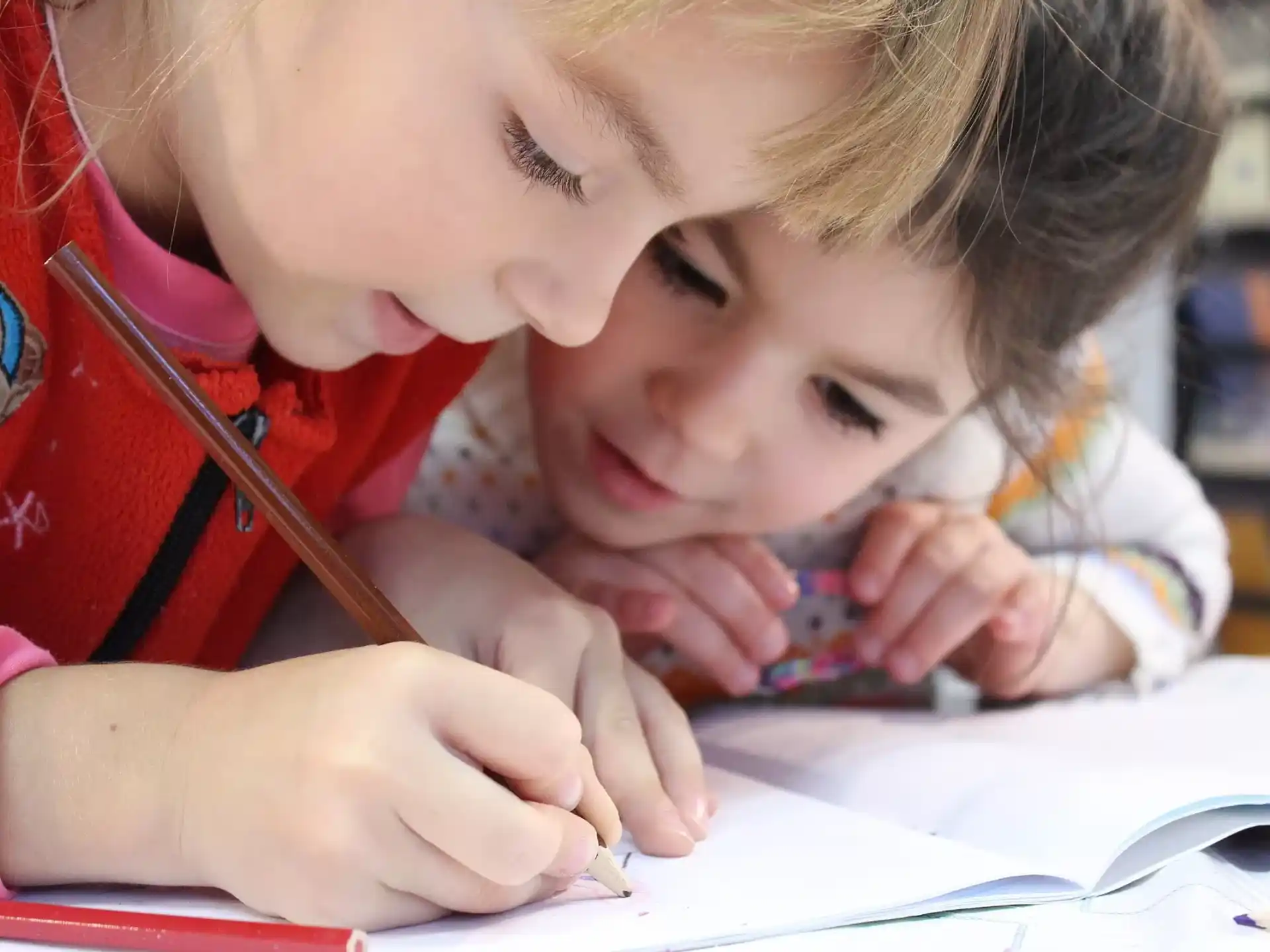 a young girl and a young boy looking at a book