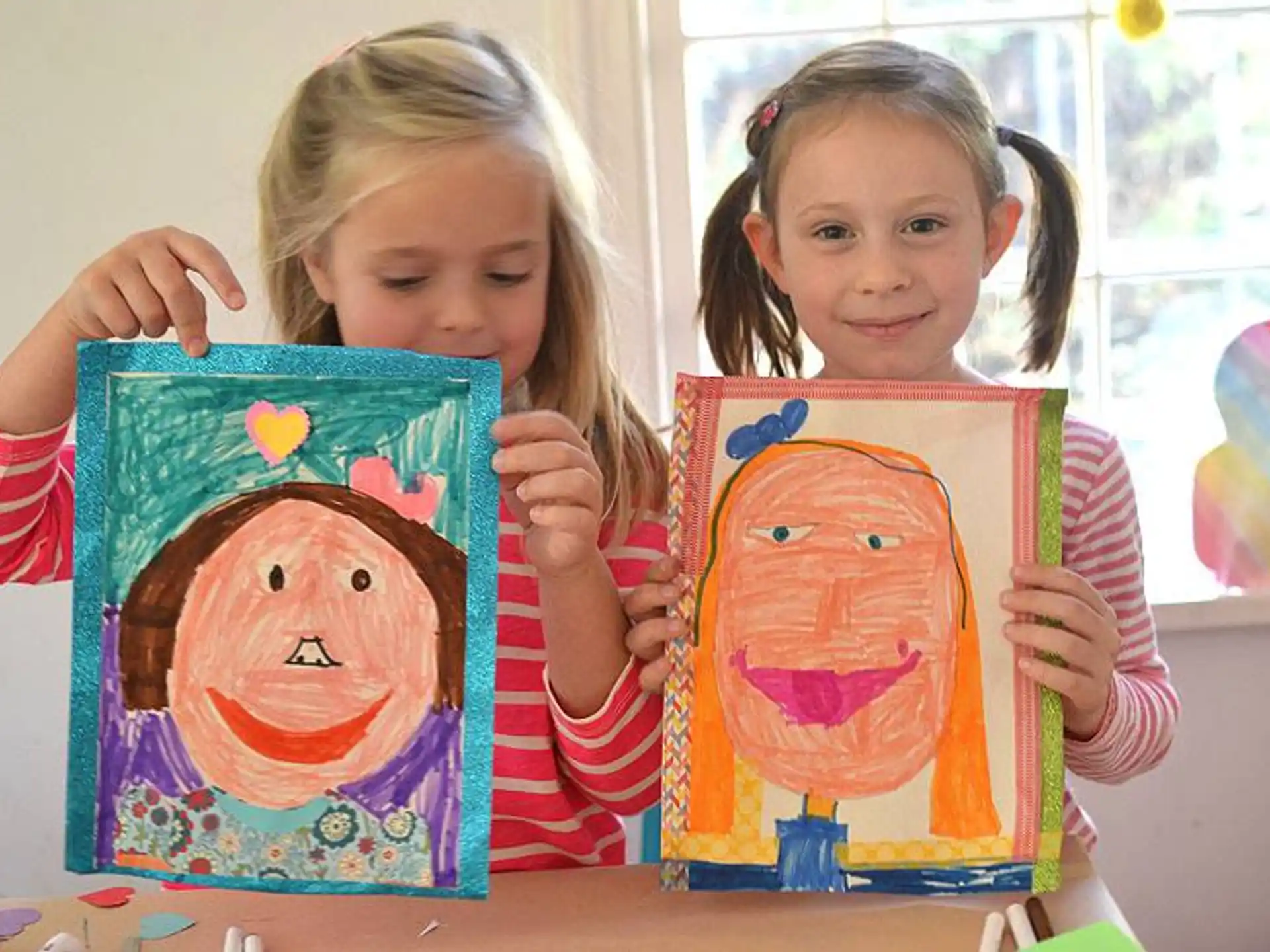 a couple of girls holding up artwork
