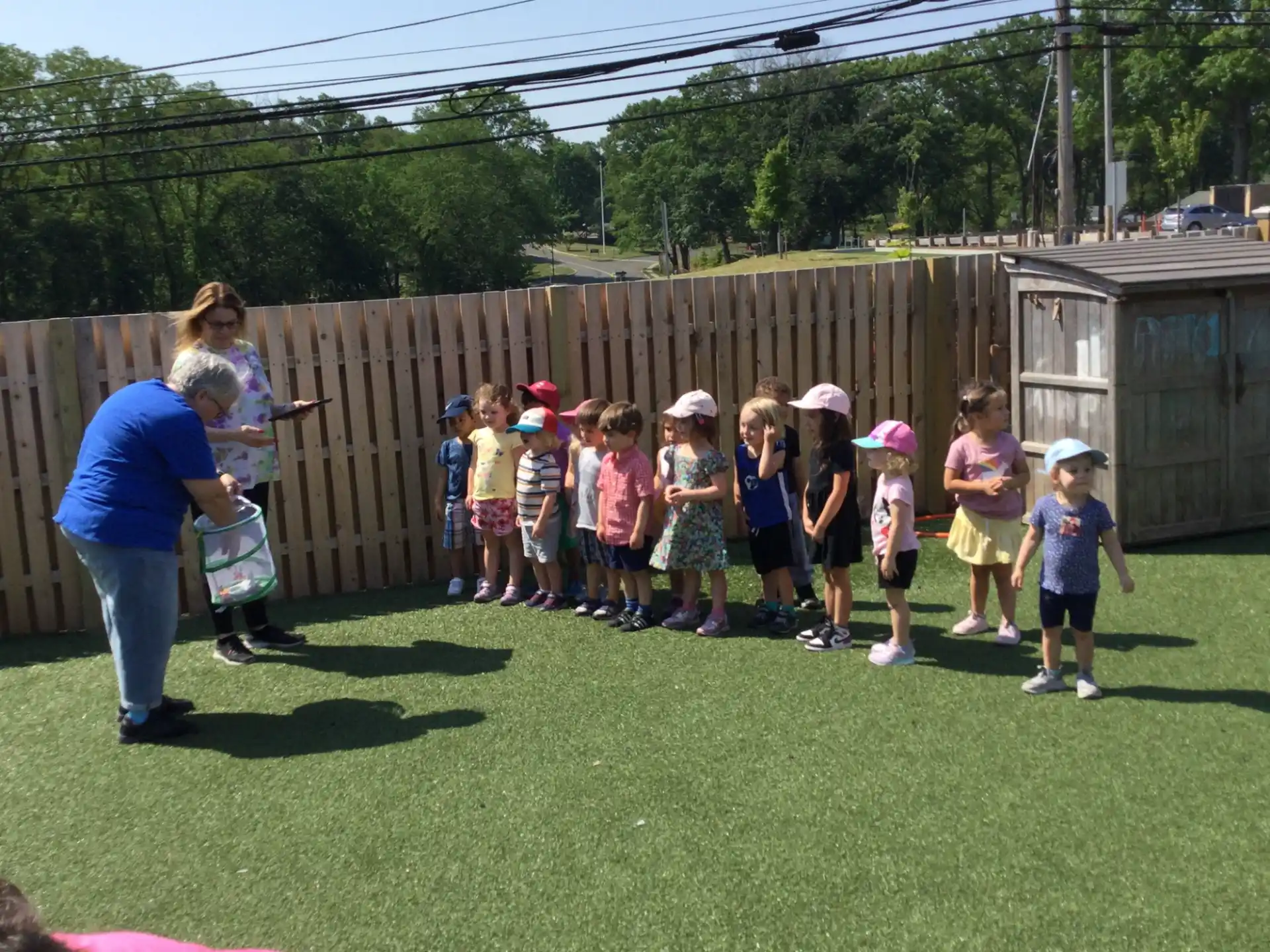 a person and a group of children standing in a grassy area
