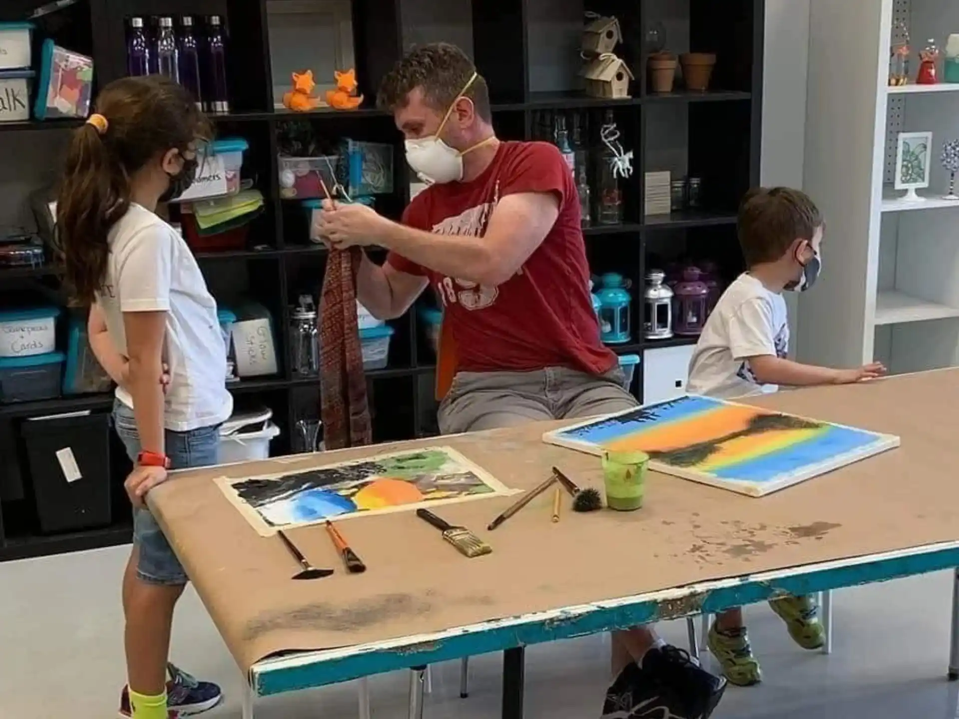 a man and a woman with a child painting on a table