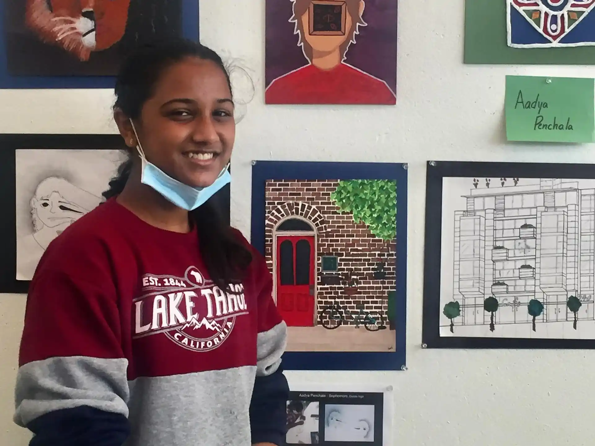 a person smiling in front of a wall with posters