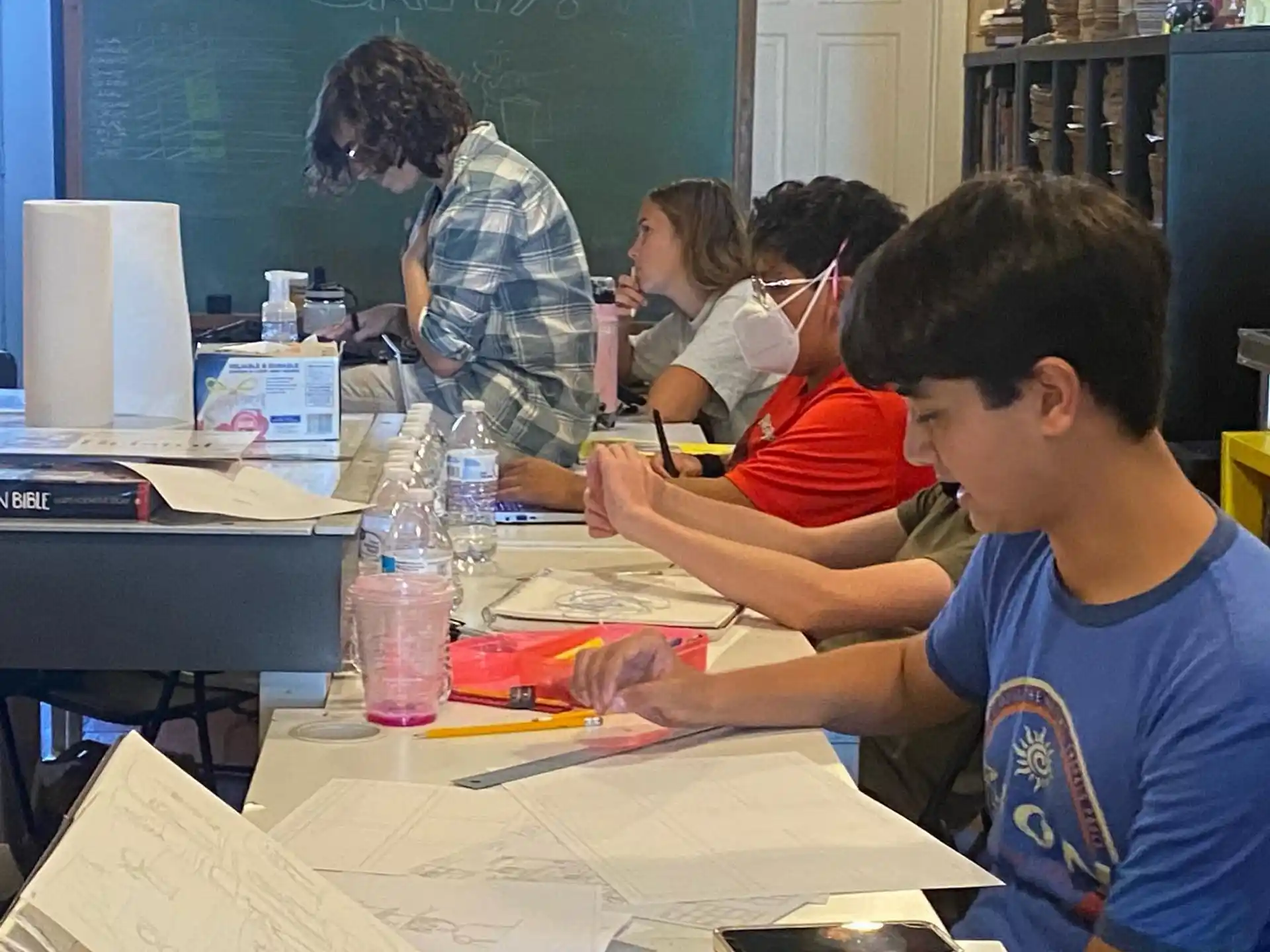 a group of people sitting at a table in a classroom