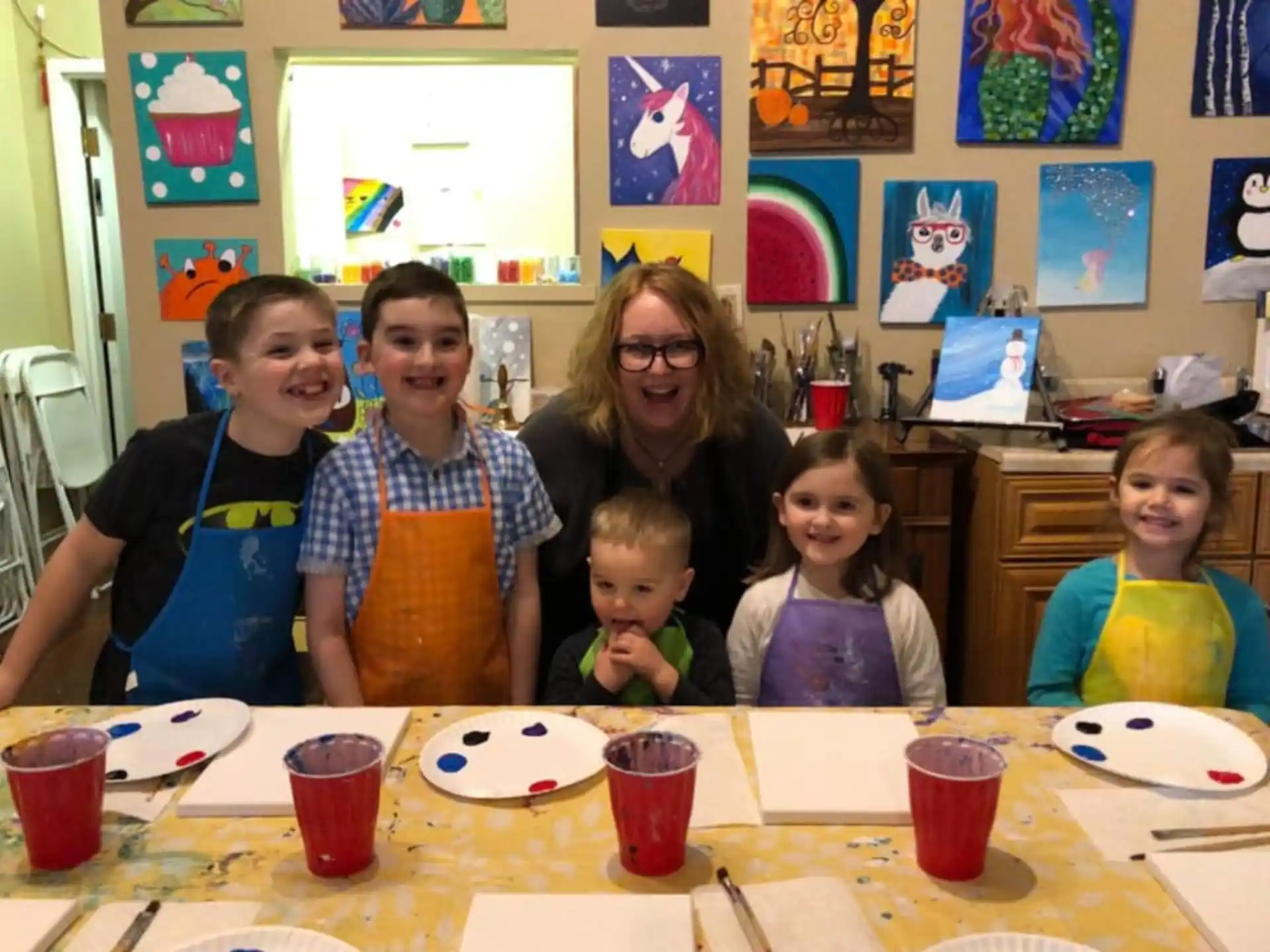 a group of children sitting at a table with cups and plates