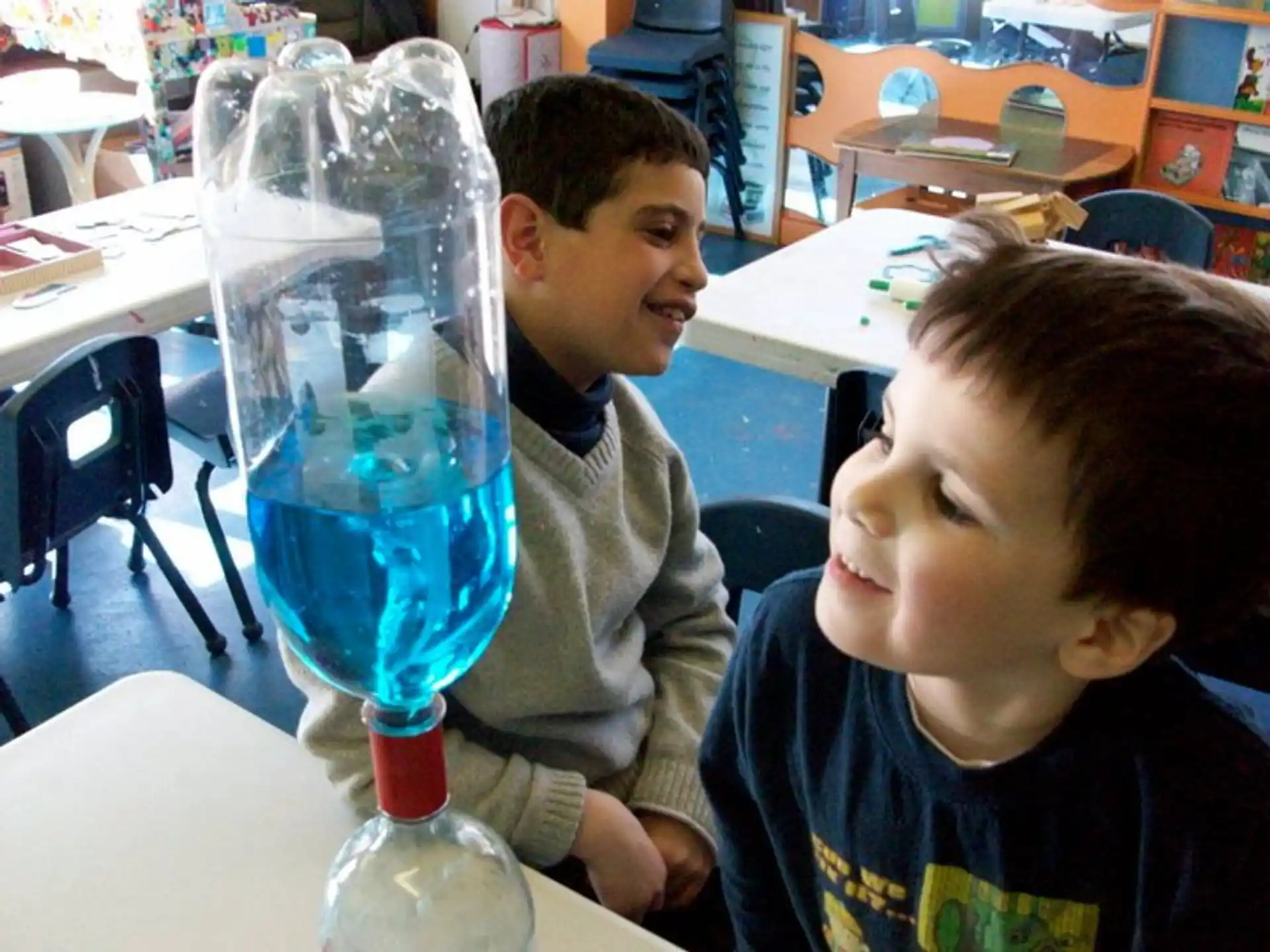 a person and a boy sitting at a table with a water bottle