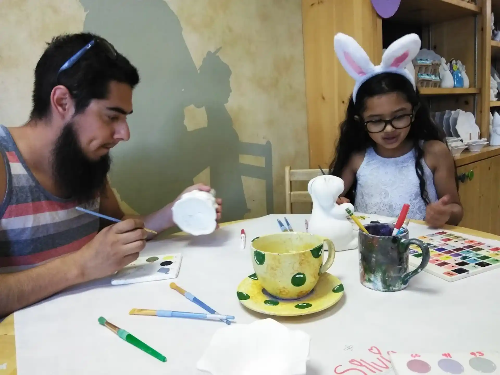 a man and a girl sitting at a table with a tea set
