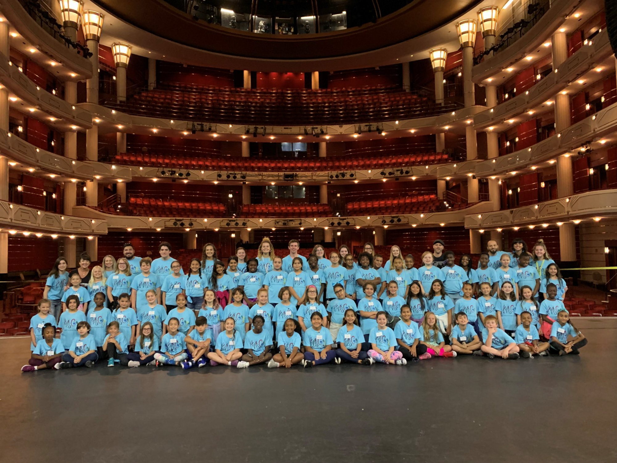 a group of people in blue and white outfits sitting on a stage