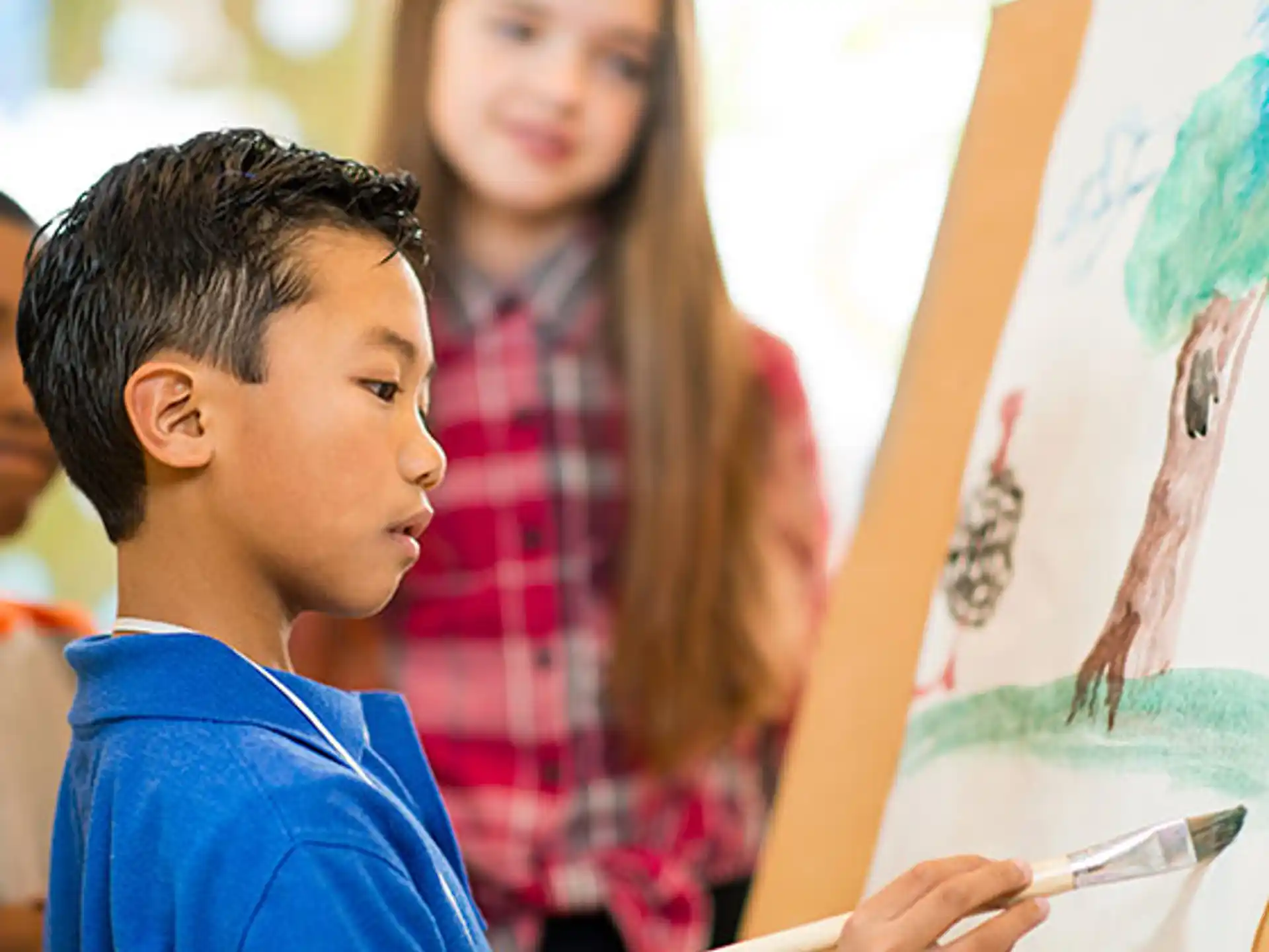 a young boy drawing on a white board