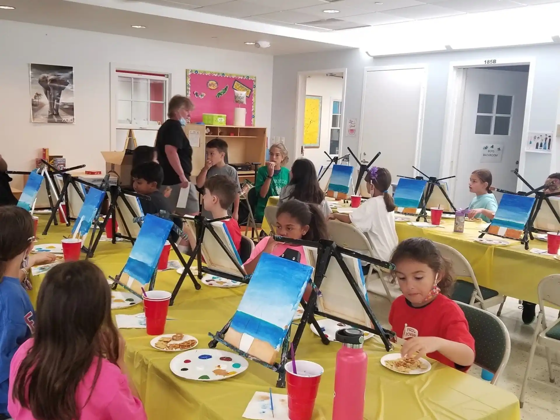 a group of children sitting at a table with laptops