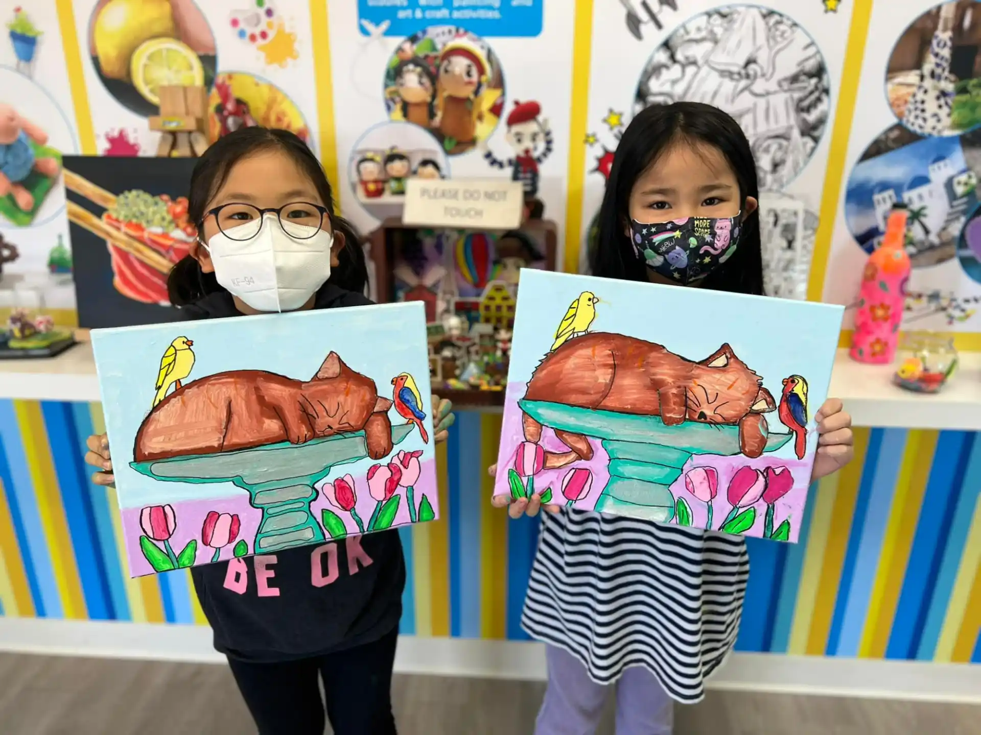 a couple of girls holding up artwork