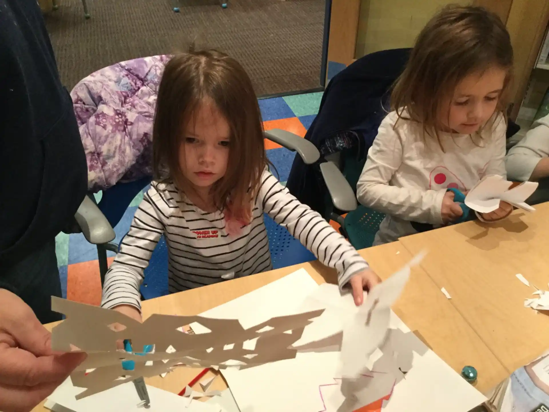 a couple of girls sitting at a table with a drawing