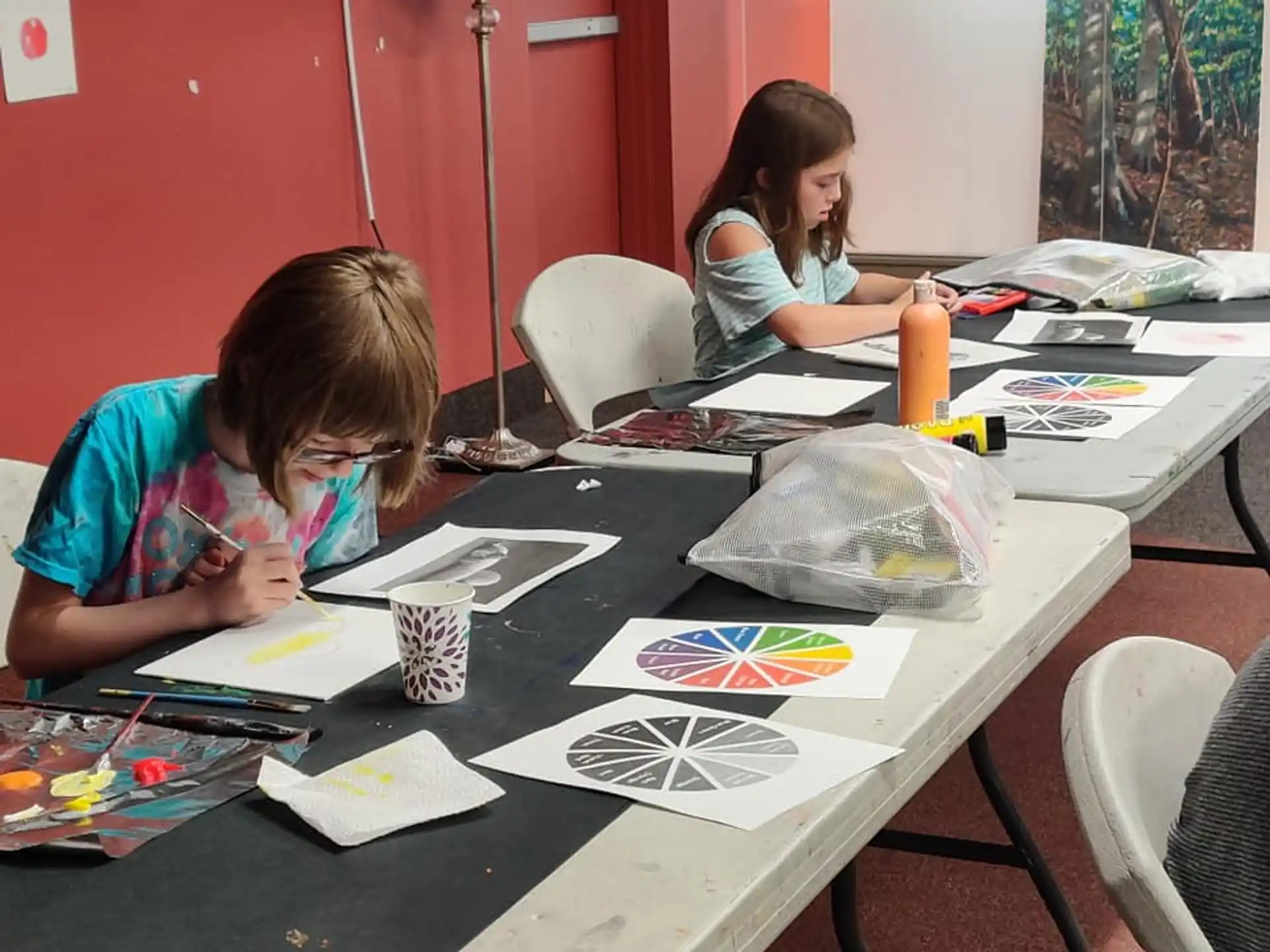 a couple of girls sitting at a table with drawings on it