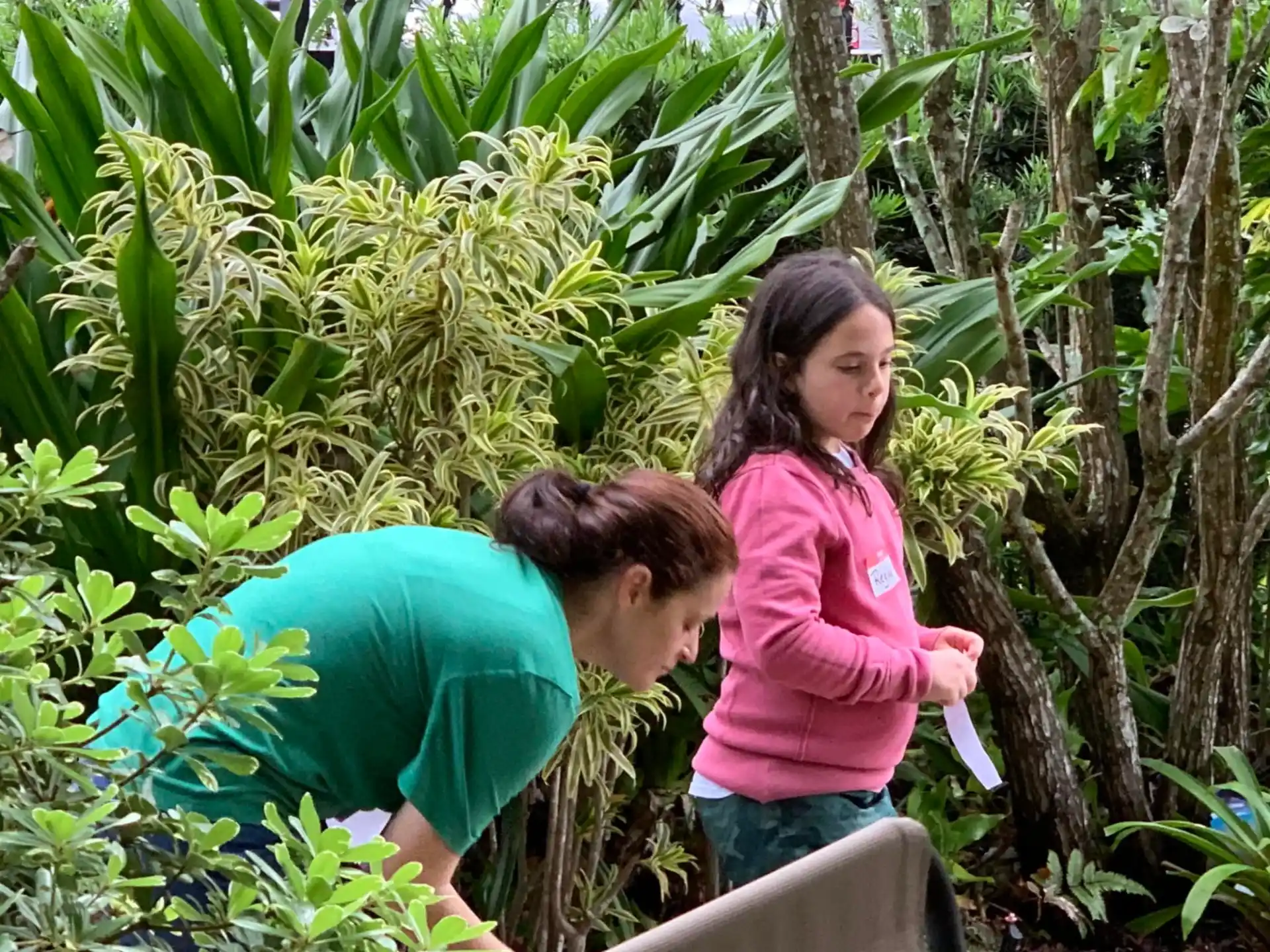 a person and a girl looking at a plant