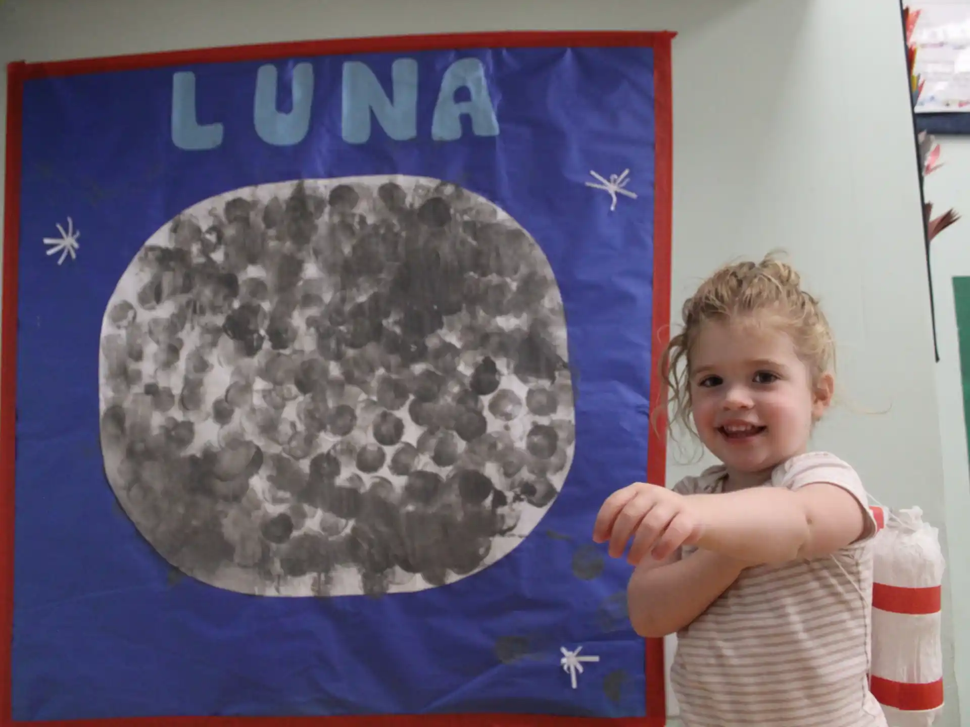 a child standing next to a painting