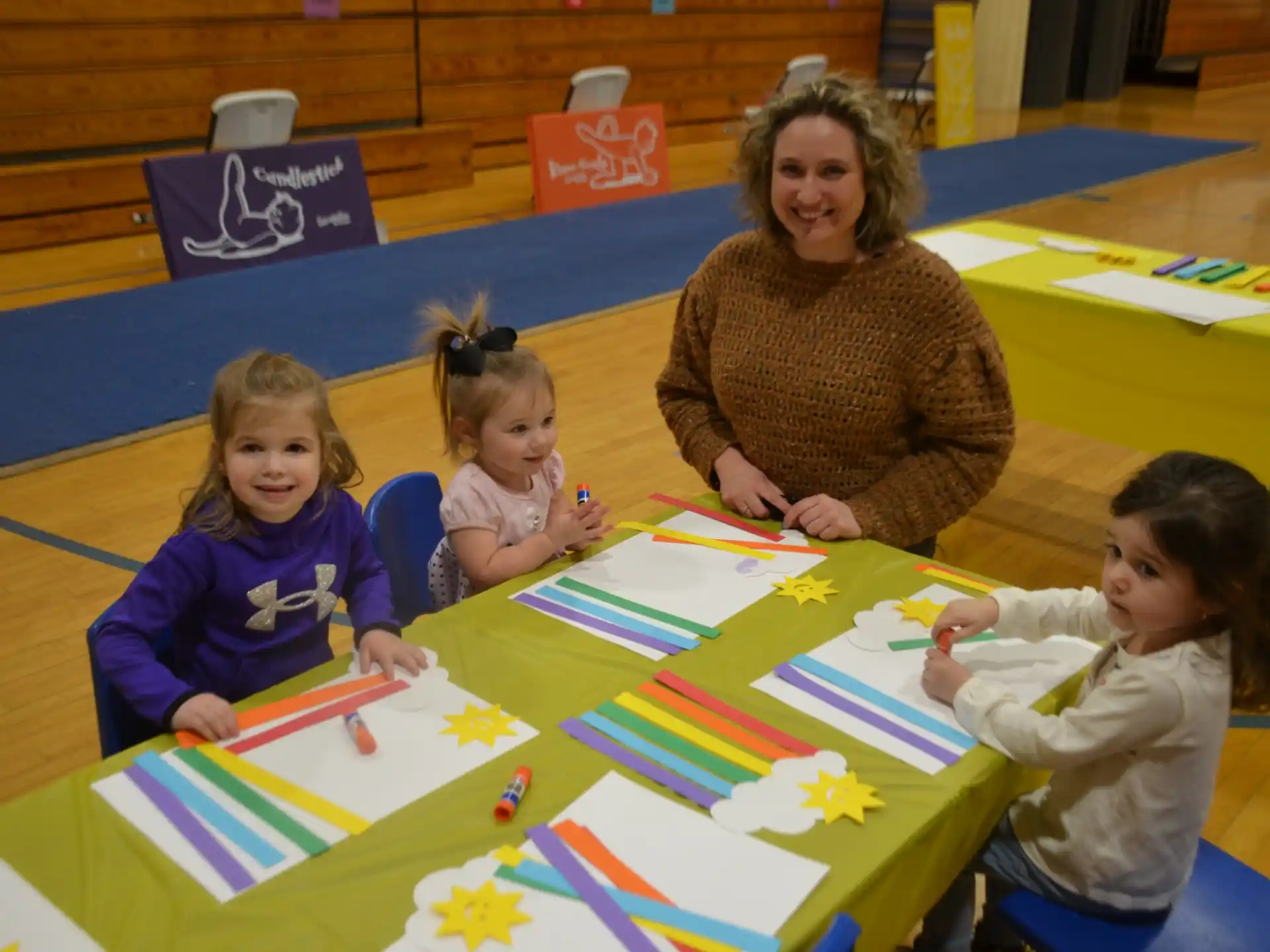 a person and several children sitting at a table with colorful paper