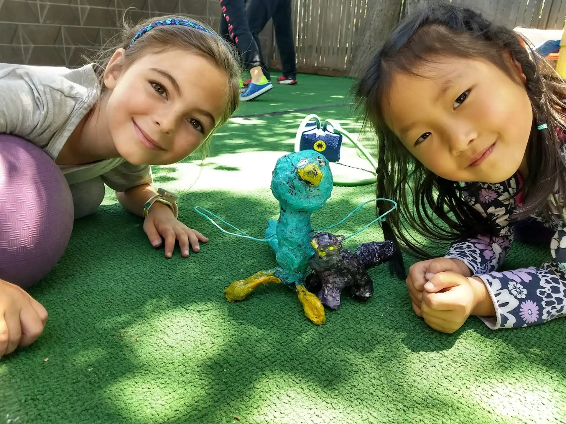 a couple of girls lying on the ground with a toy