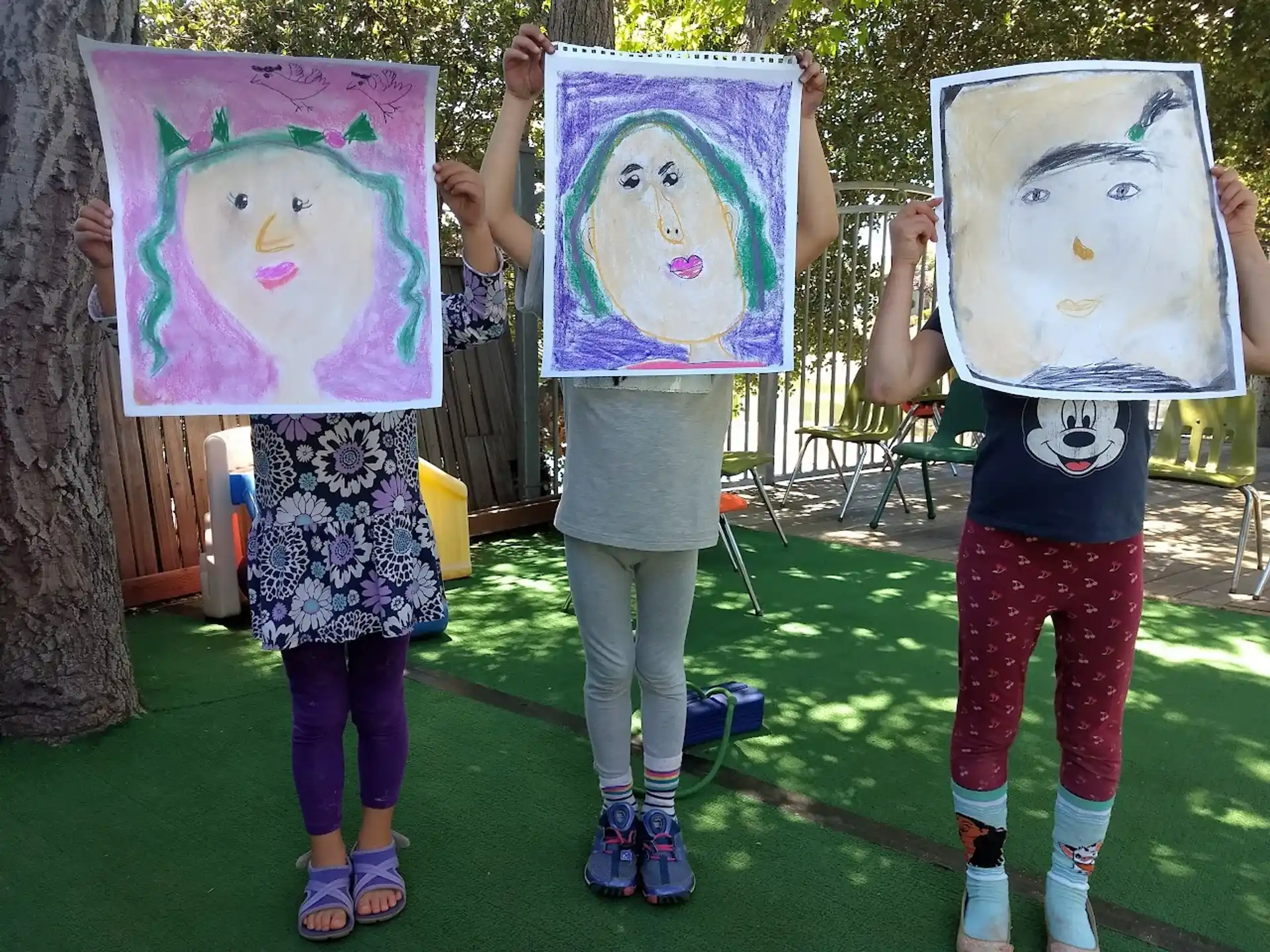 a group of girls holding up drawings