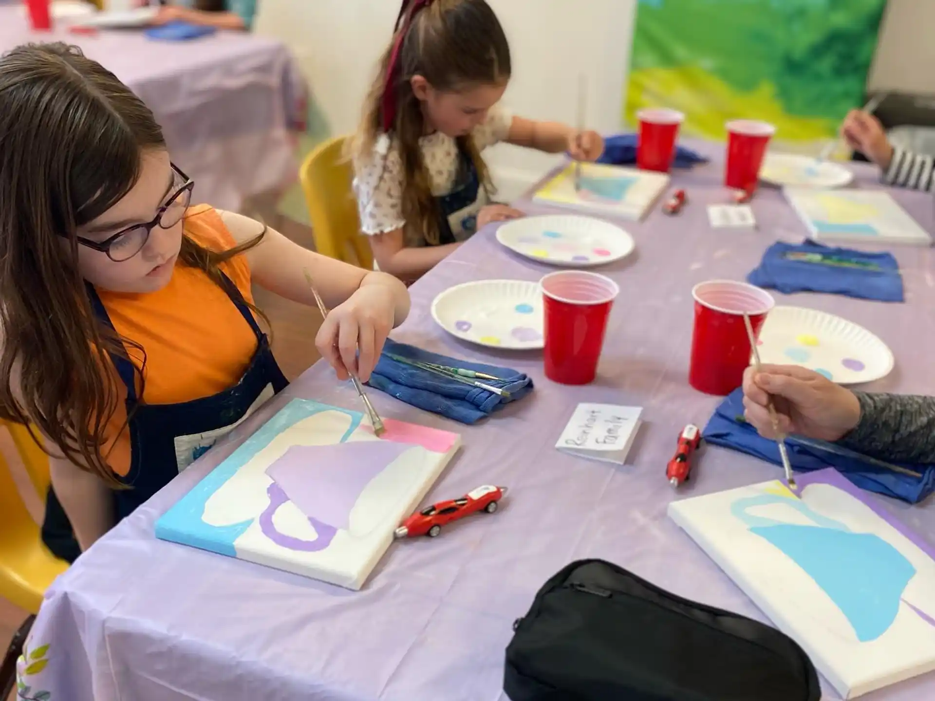 a group of children sitting at a table with paper and pencils