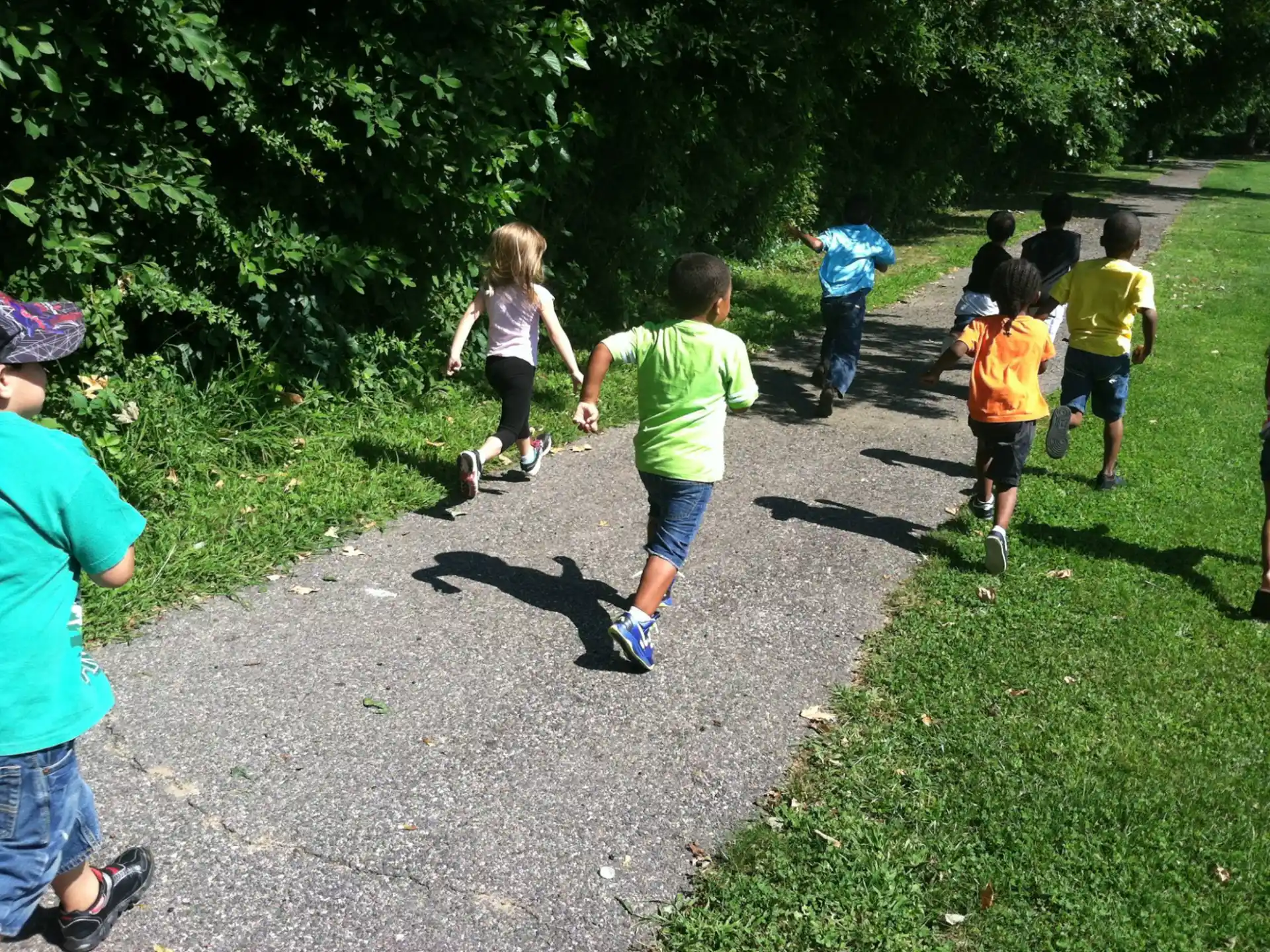 a group of children running on a path in a park