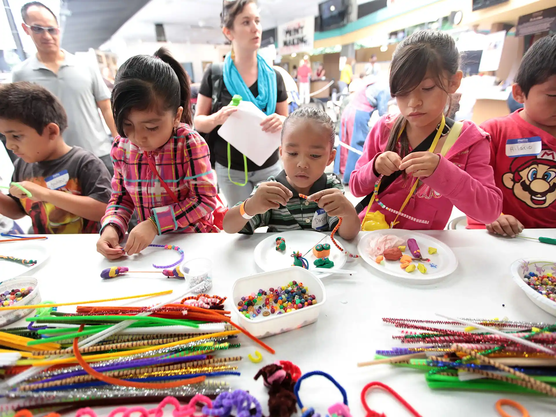 a group of children sitting at a table with a colorful tablecloth
