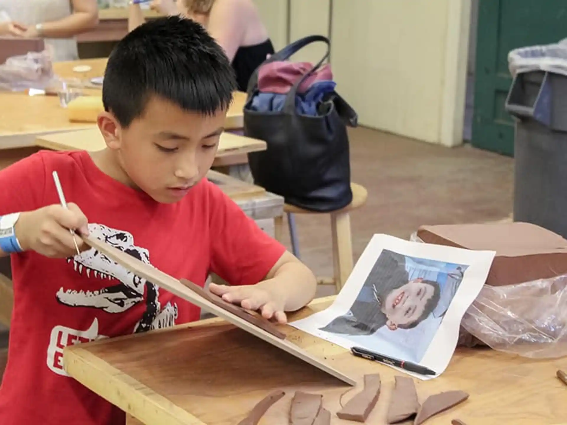 a young boy sitting at a table writing on a book