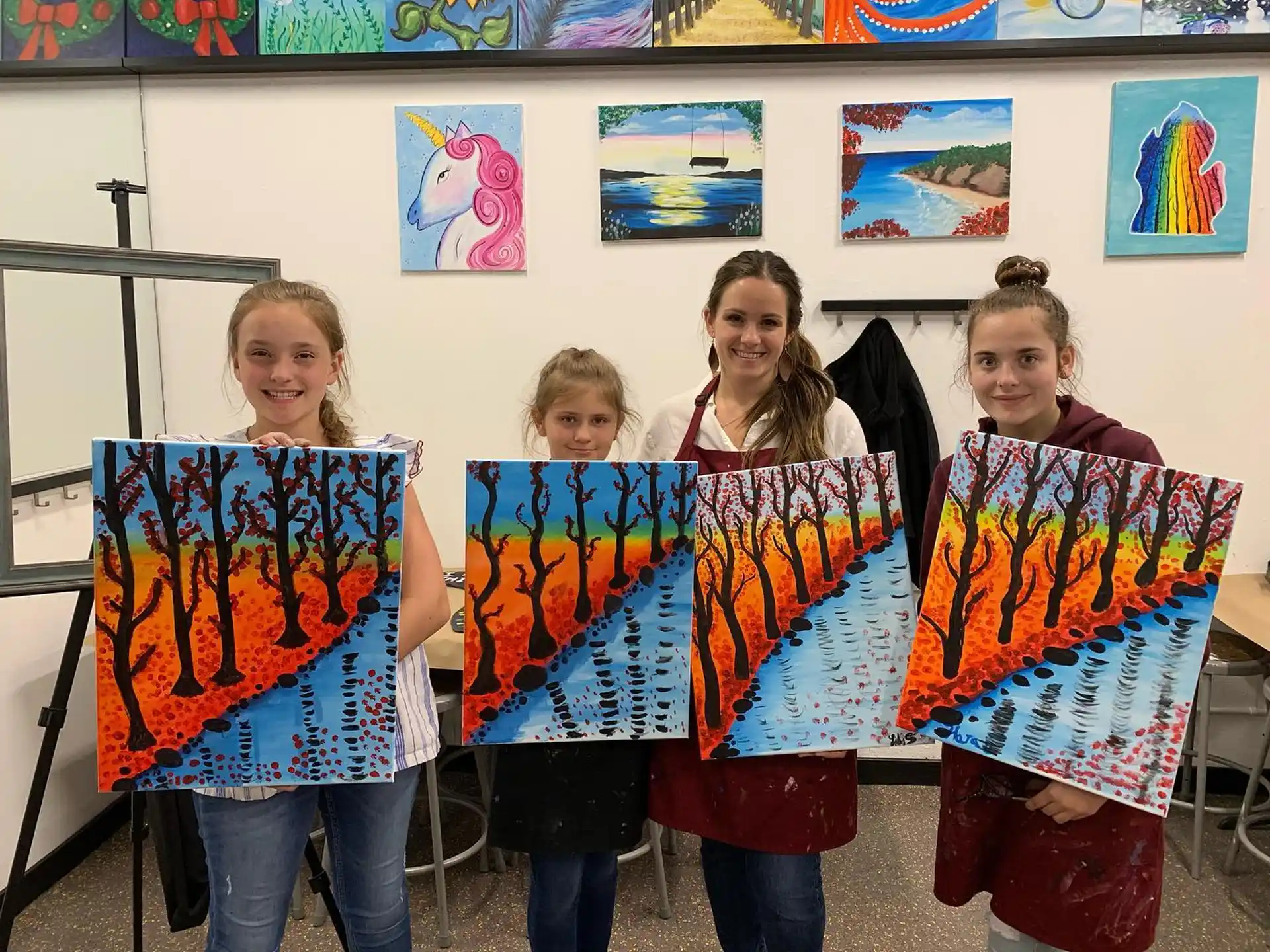 a group of girls holding paintings