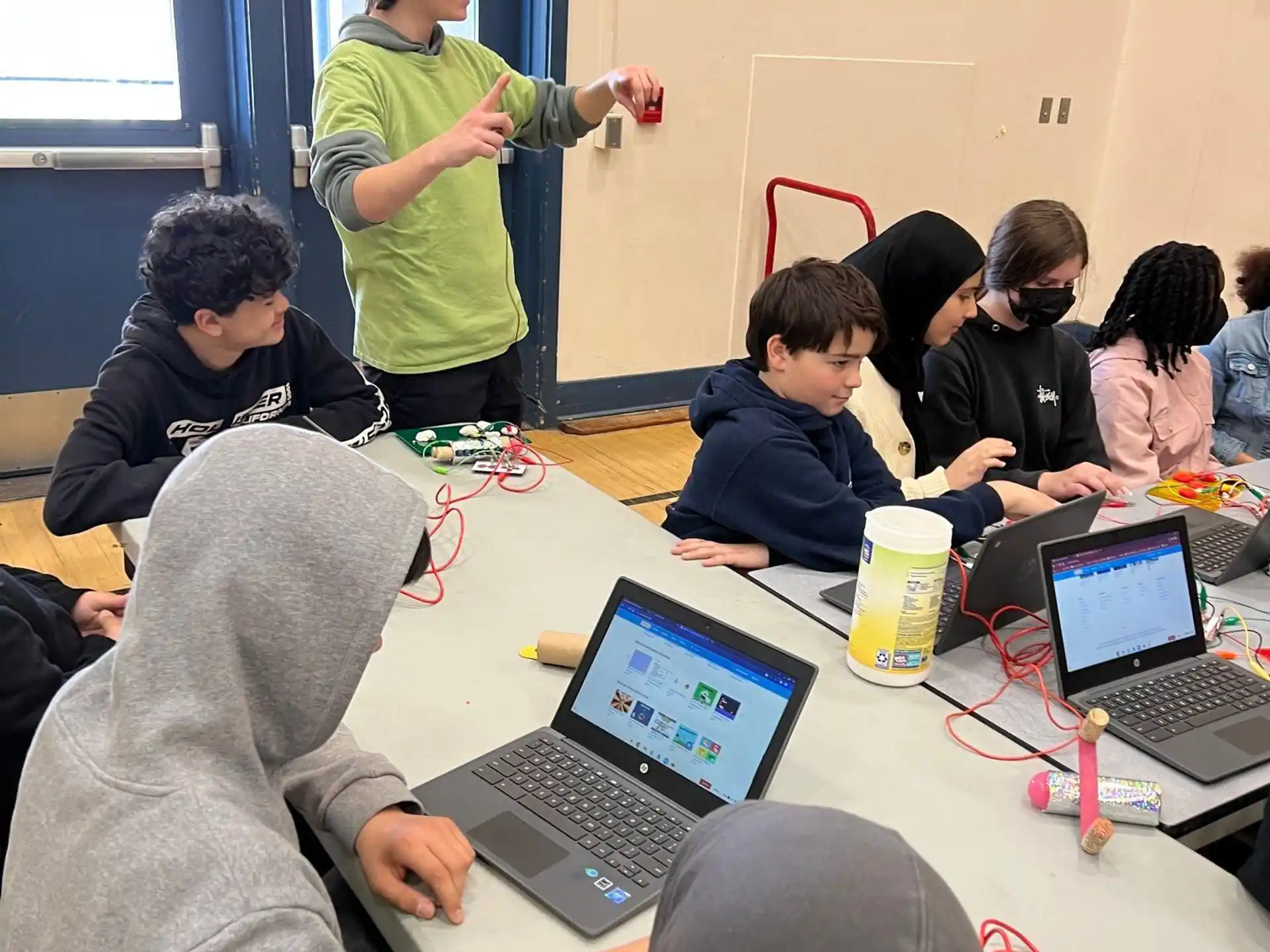 a group of people sitting around a table with laptops