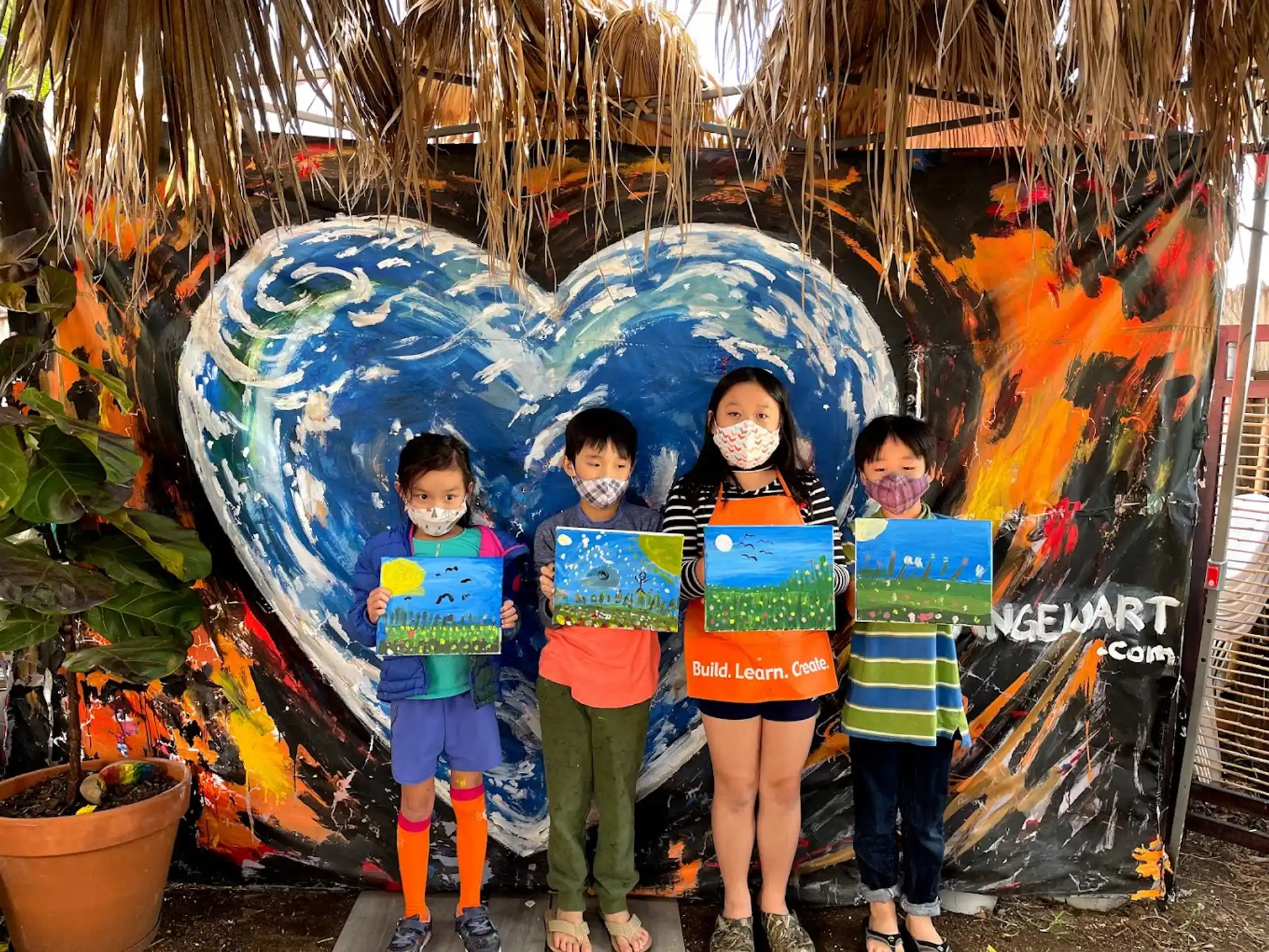 a group of children posing for a photo in front of a painting