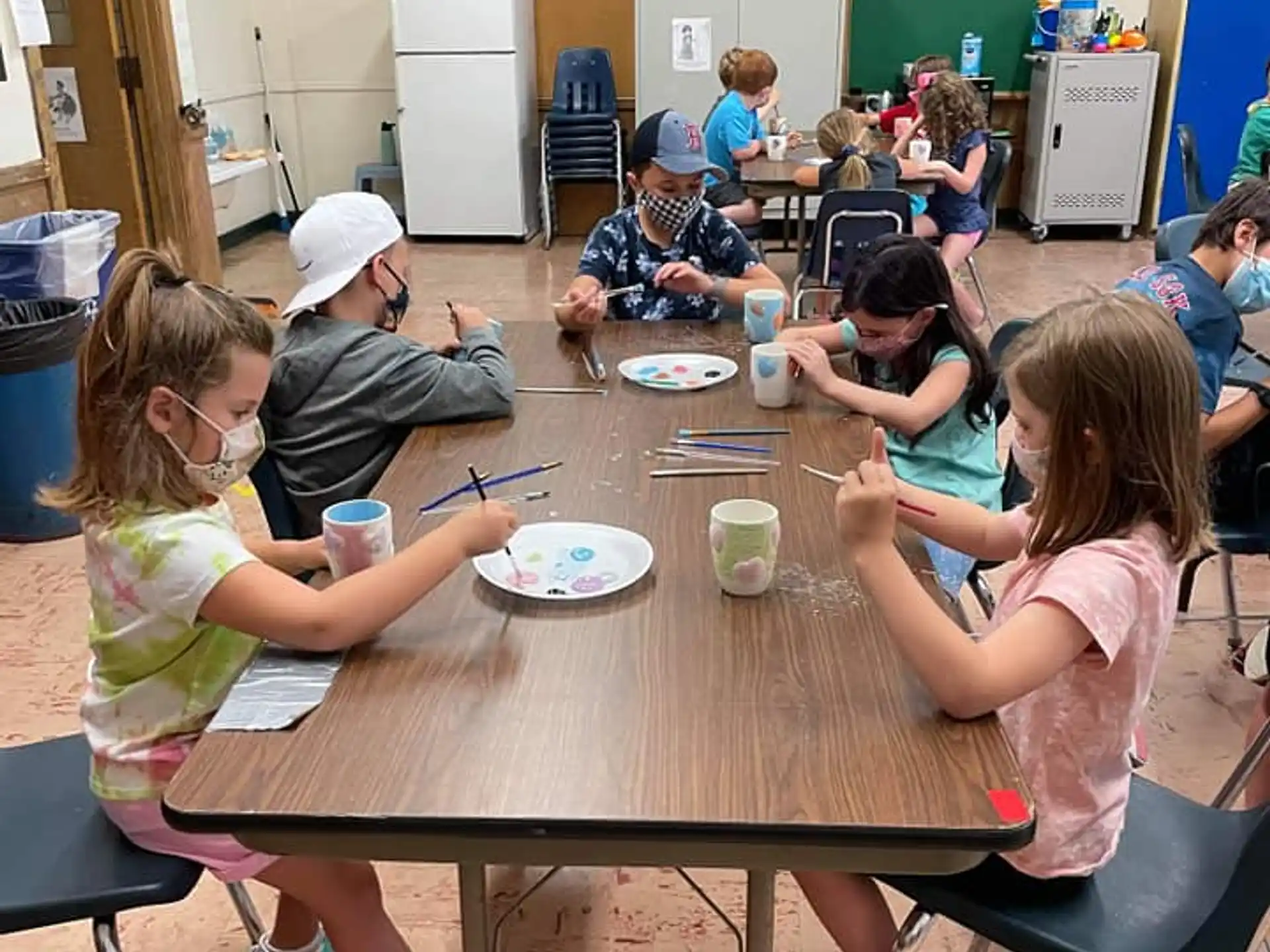 a group of children sitting around a table eating food