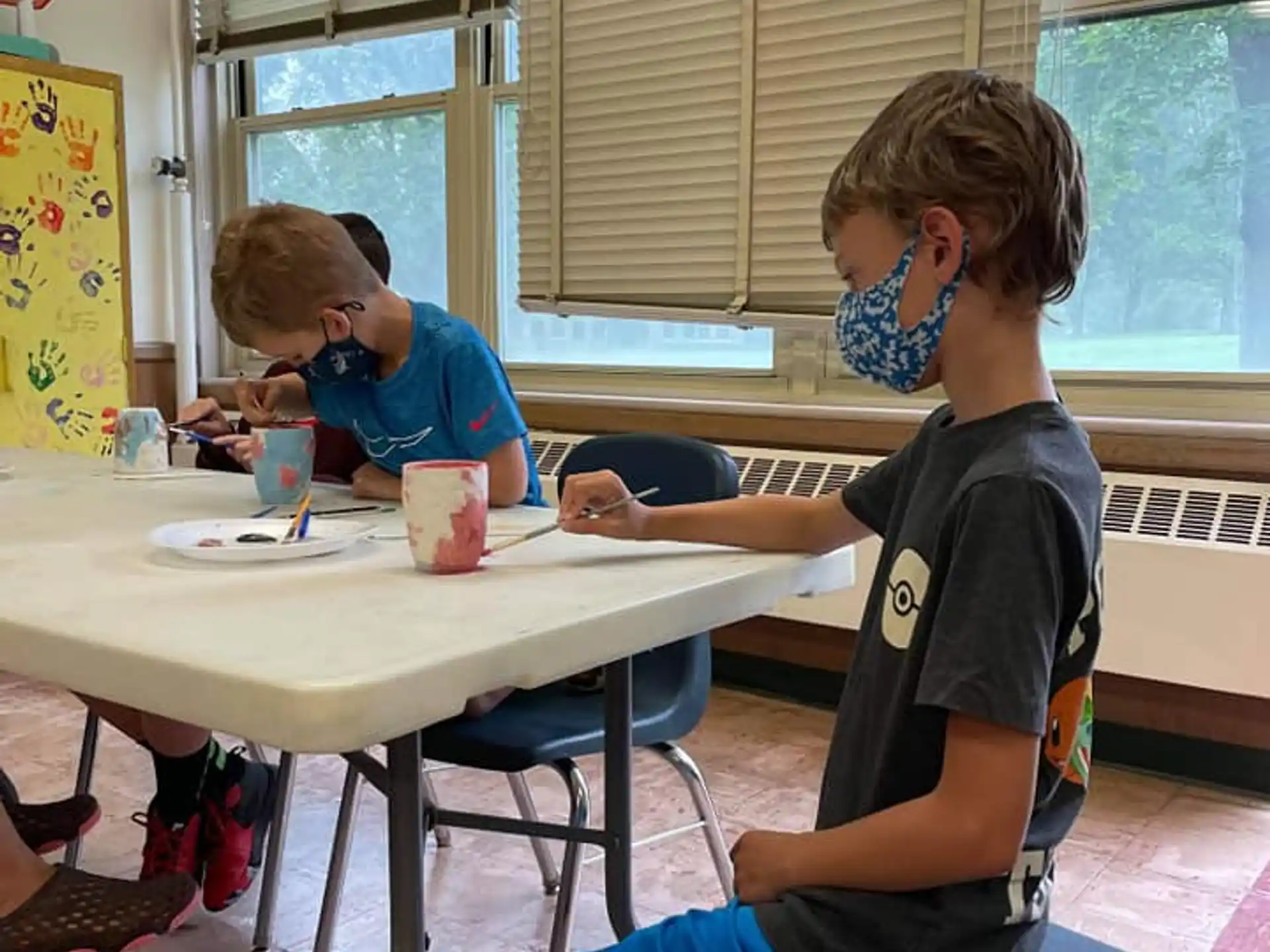 a group of kids sitting at a table with a mask on