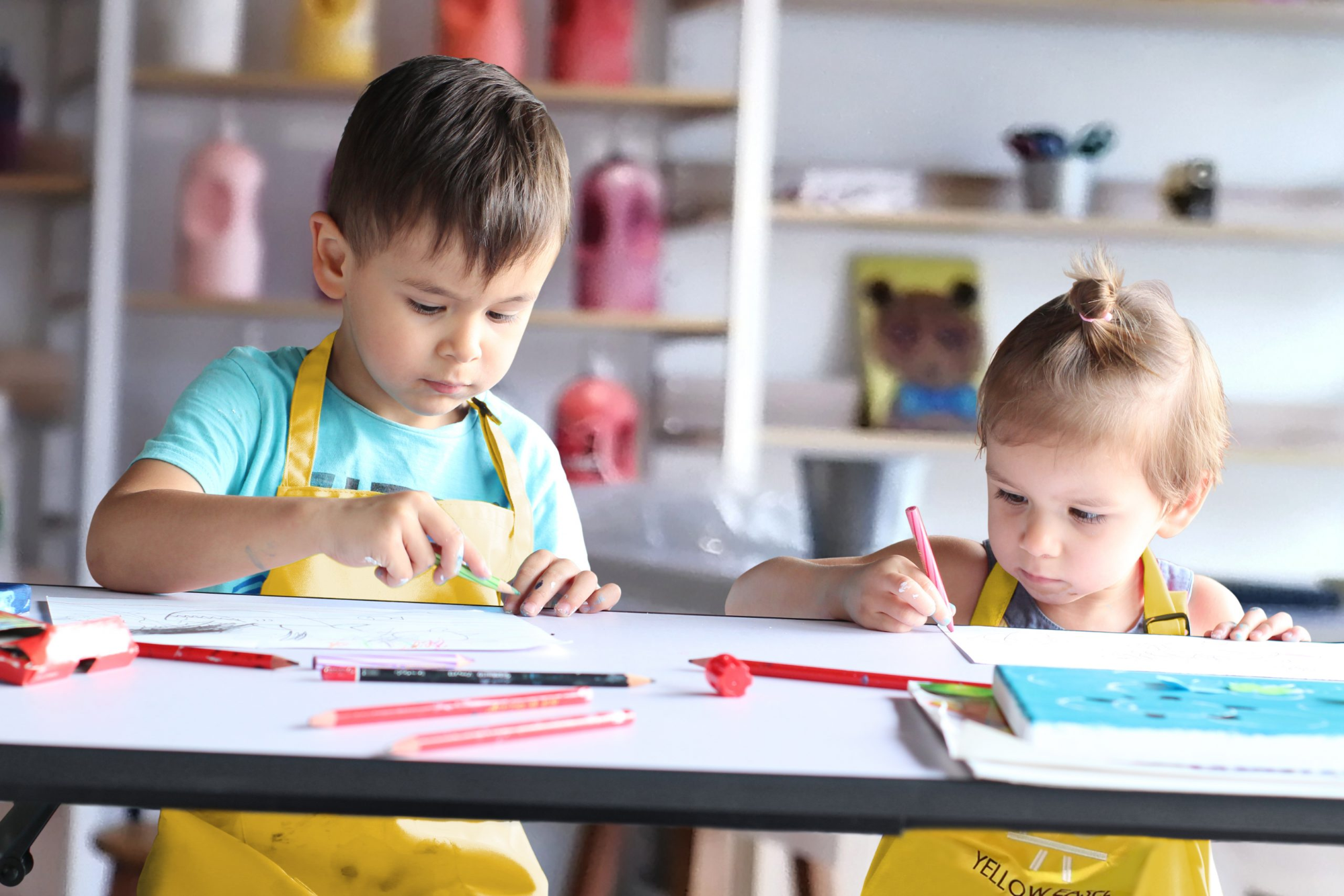 a couple of kids sitting at a table looking at a paper