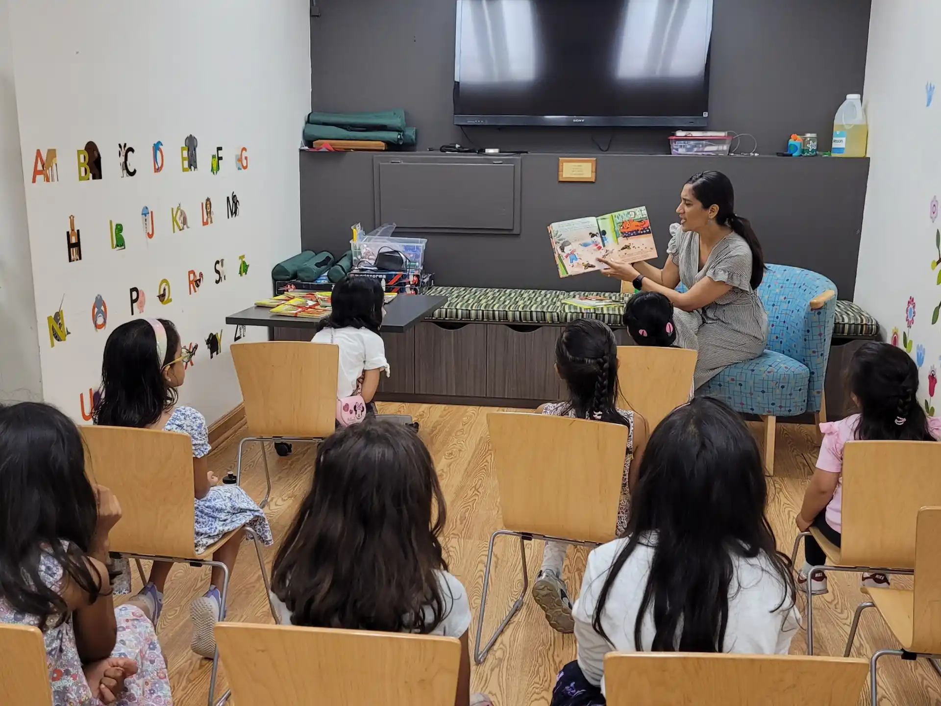 a person reading a book to a group of children in a classroom