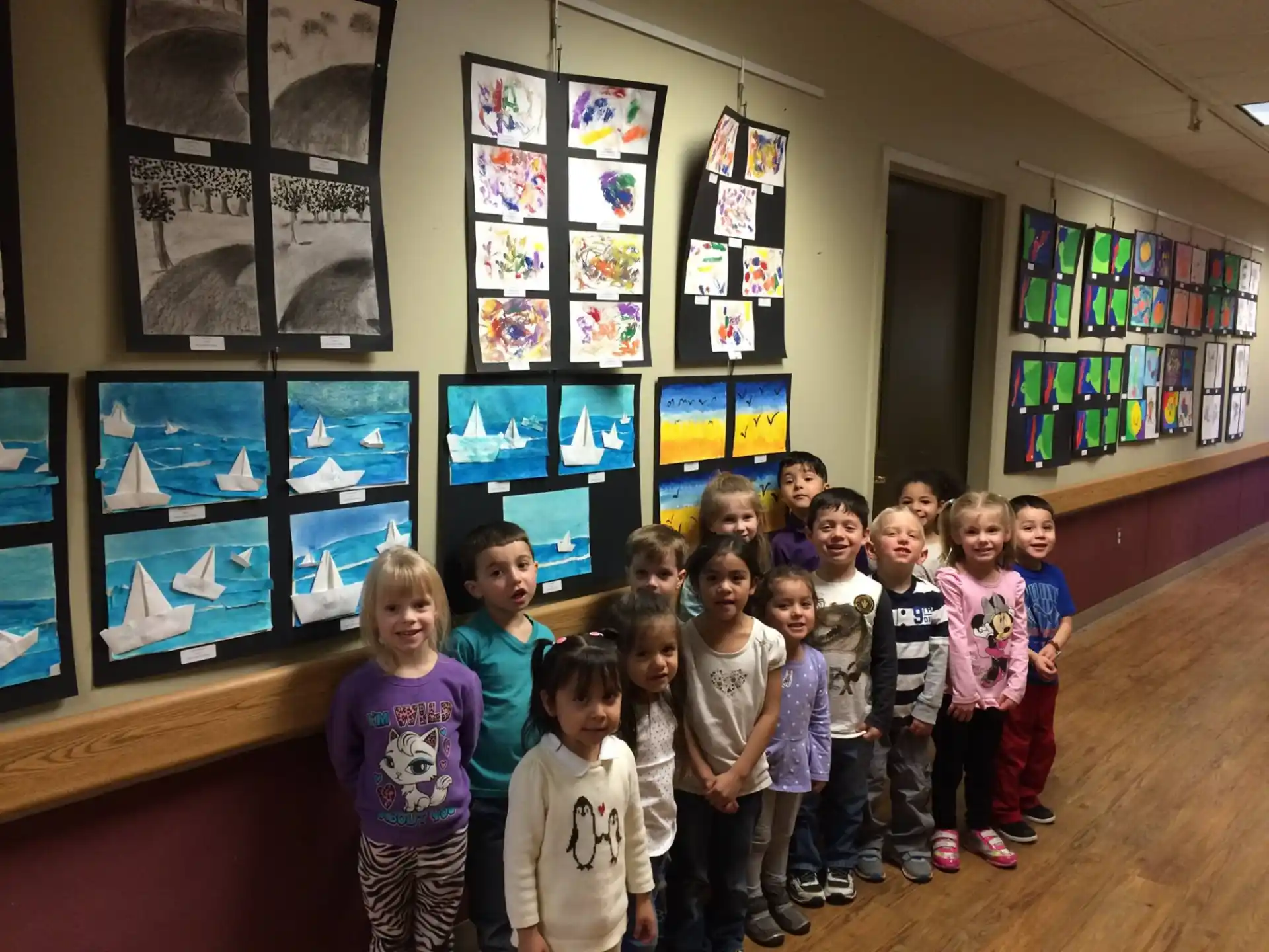 a group of children posing for a photo in front of a display of pictures