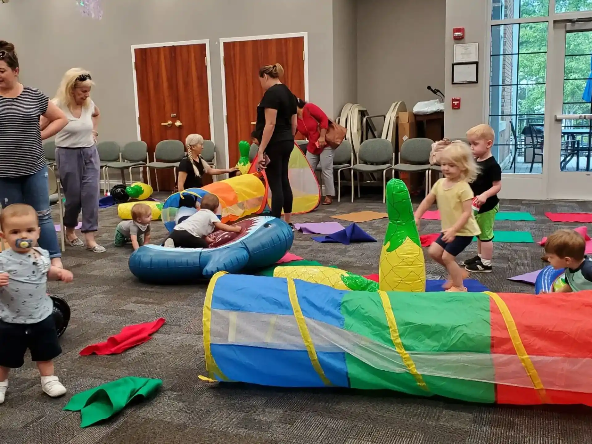a group of children playing on a mat in a room with a large window