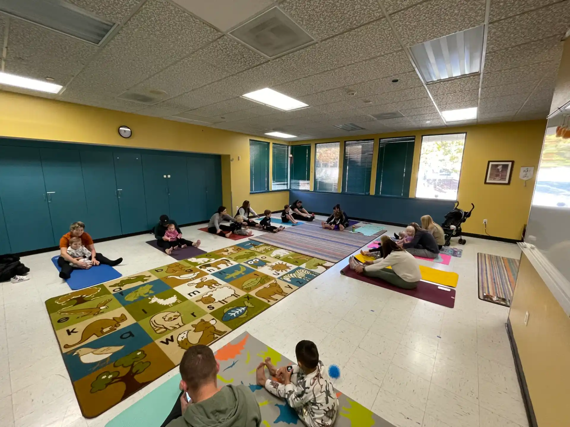 a group of people sitting on mats in a room with a large window