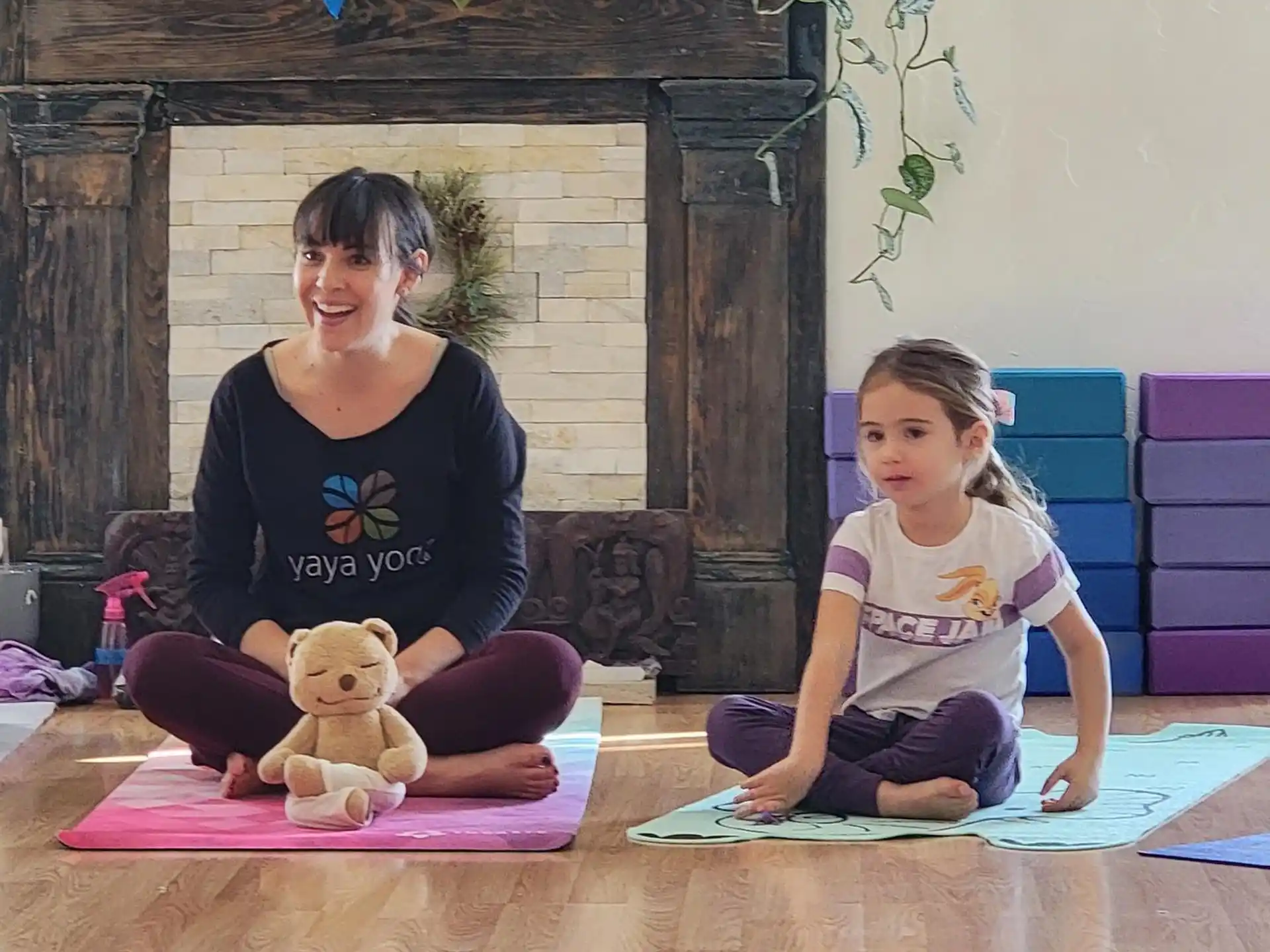 a person and a girl sitting on mats in front of a fireplace