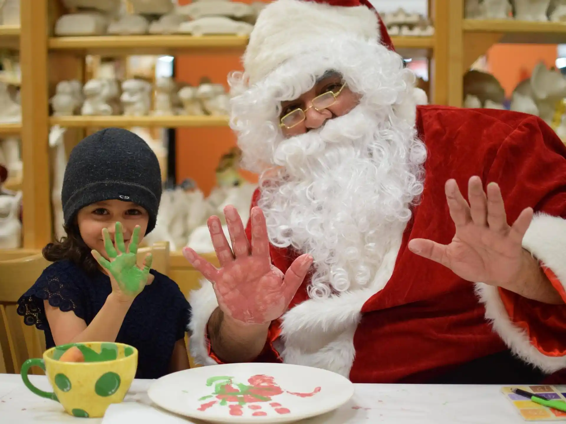 a person in a santa suit and a little girl sitting at a table
