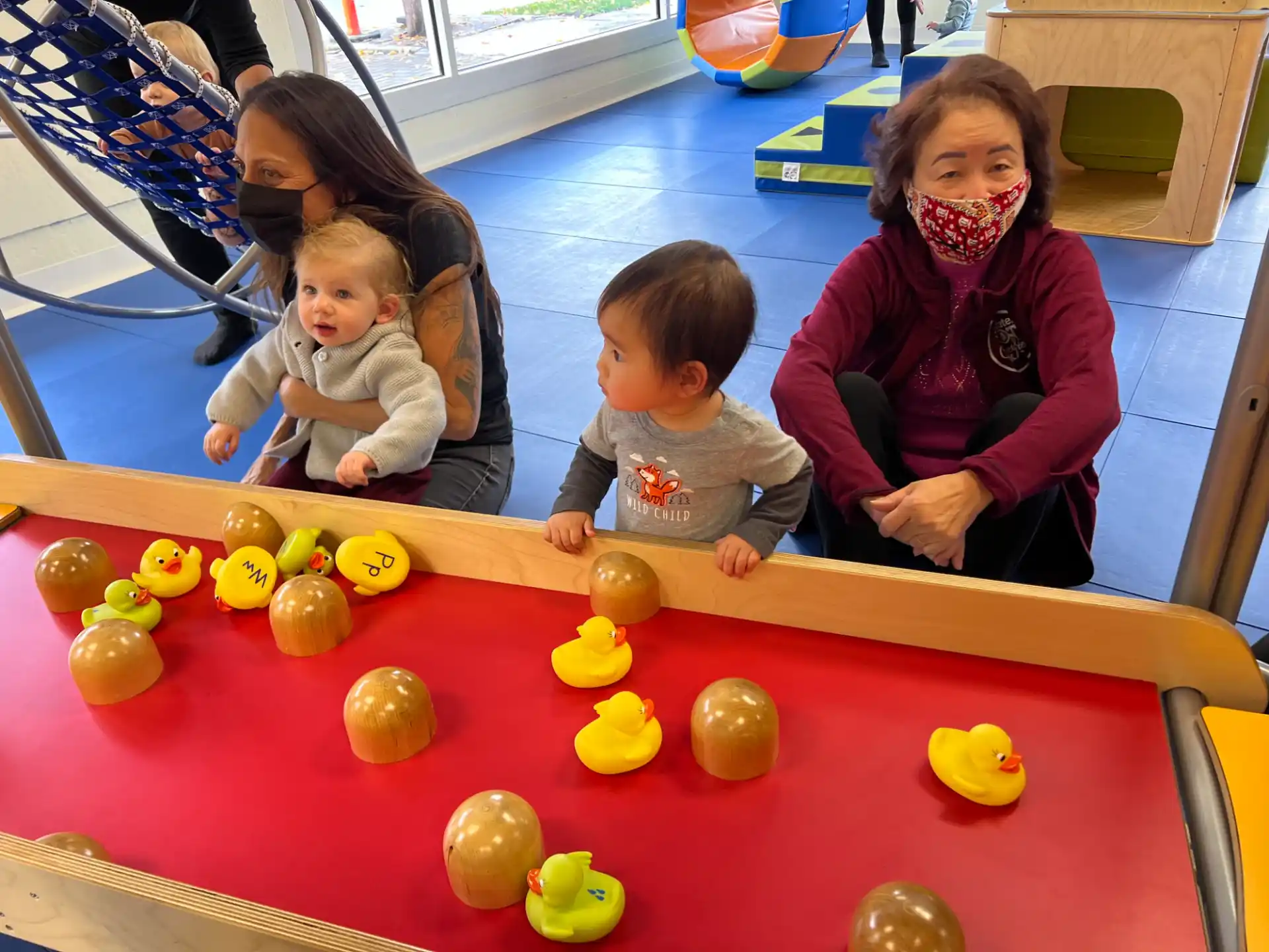 a group of children sitting on a red table with balls on it