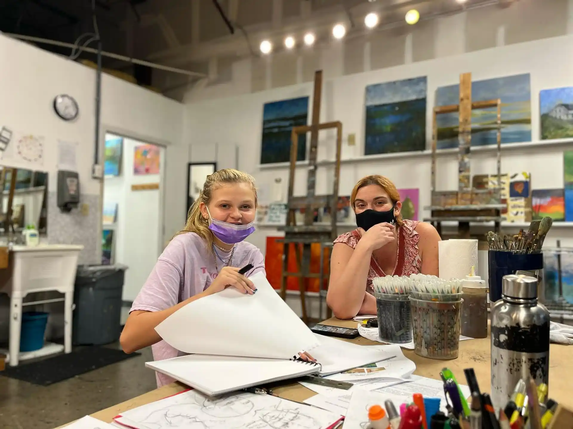 a person in a mask sitting at a table with a person in a mask