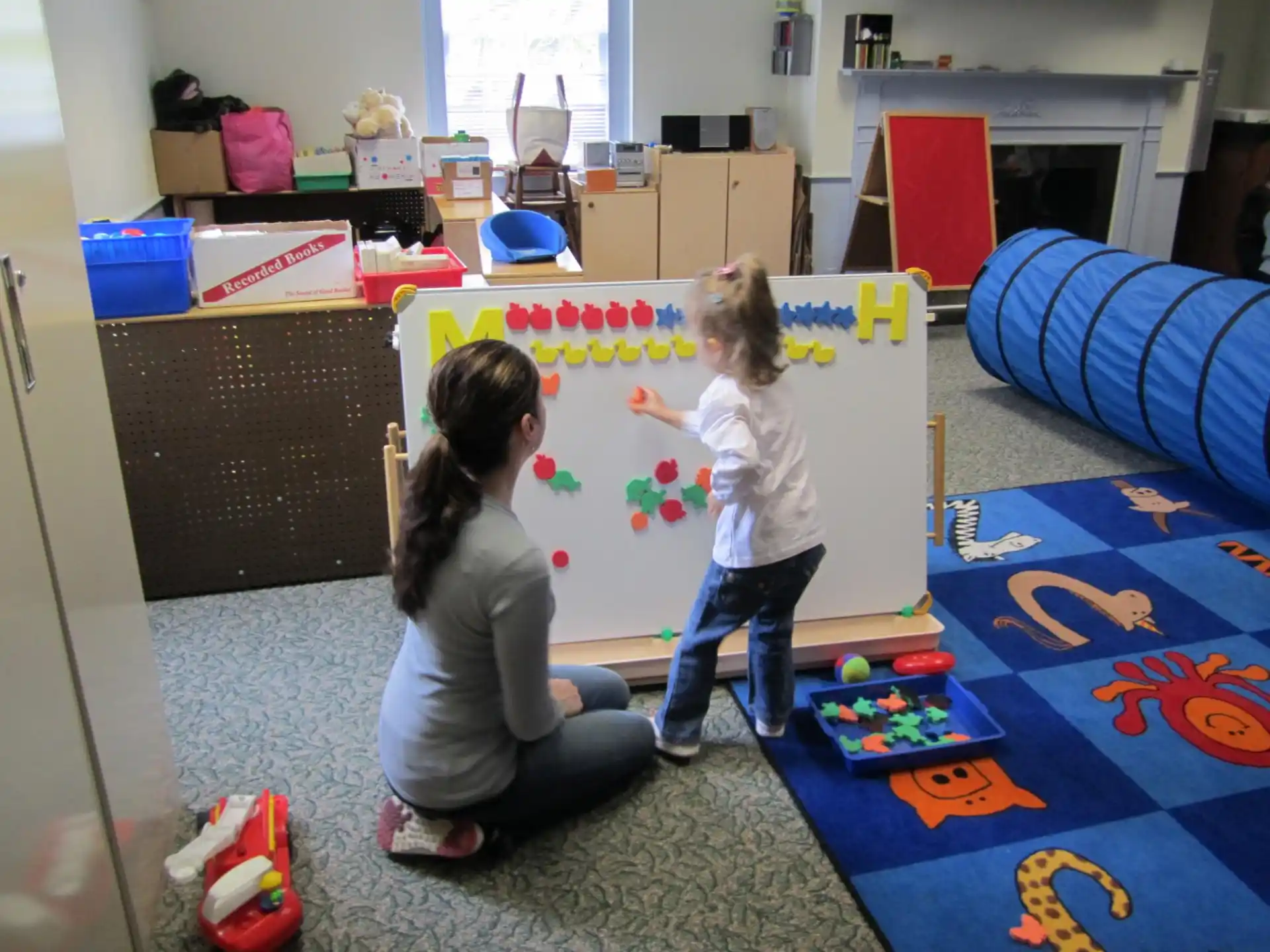 a person and a child playing with toys in a room