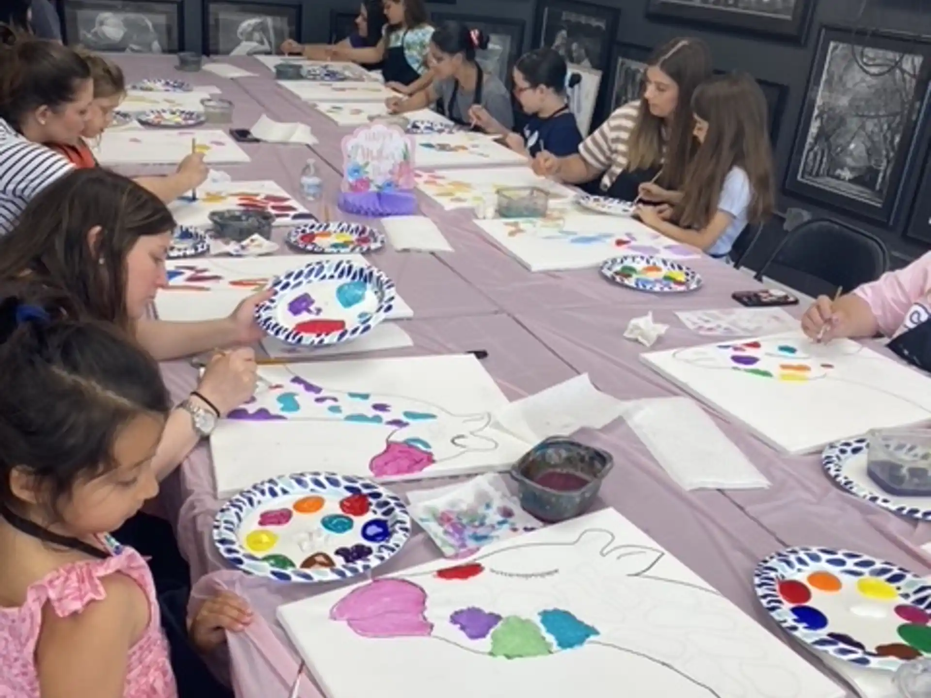 a group of children sitting around a table with colorful plates on it