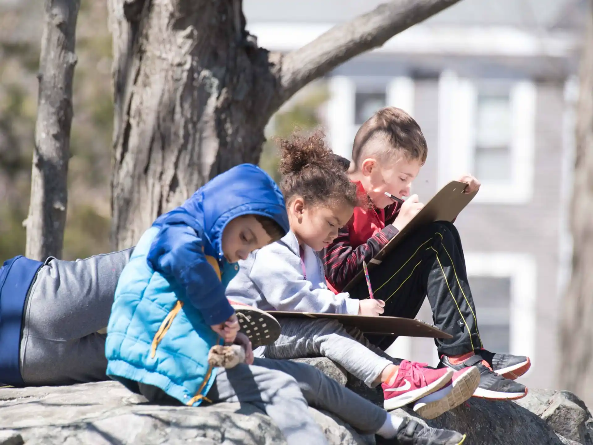 a group of kids sitting on a rock
