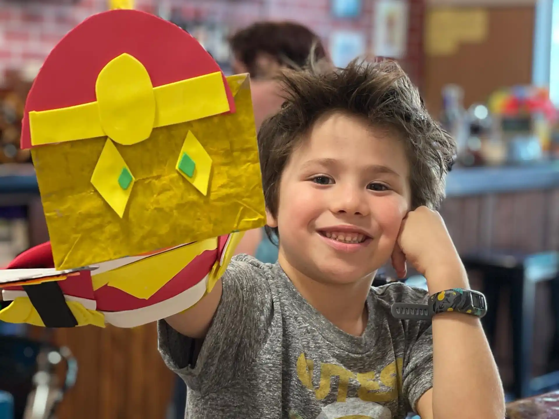 a boy sitting at a table with a colorful pinata