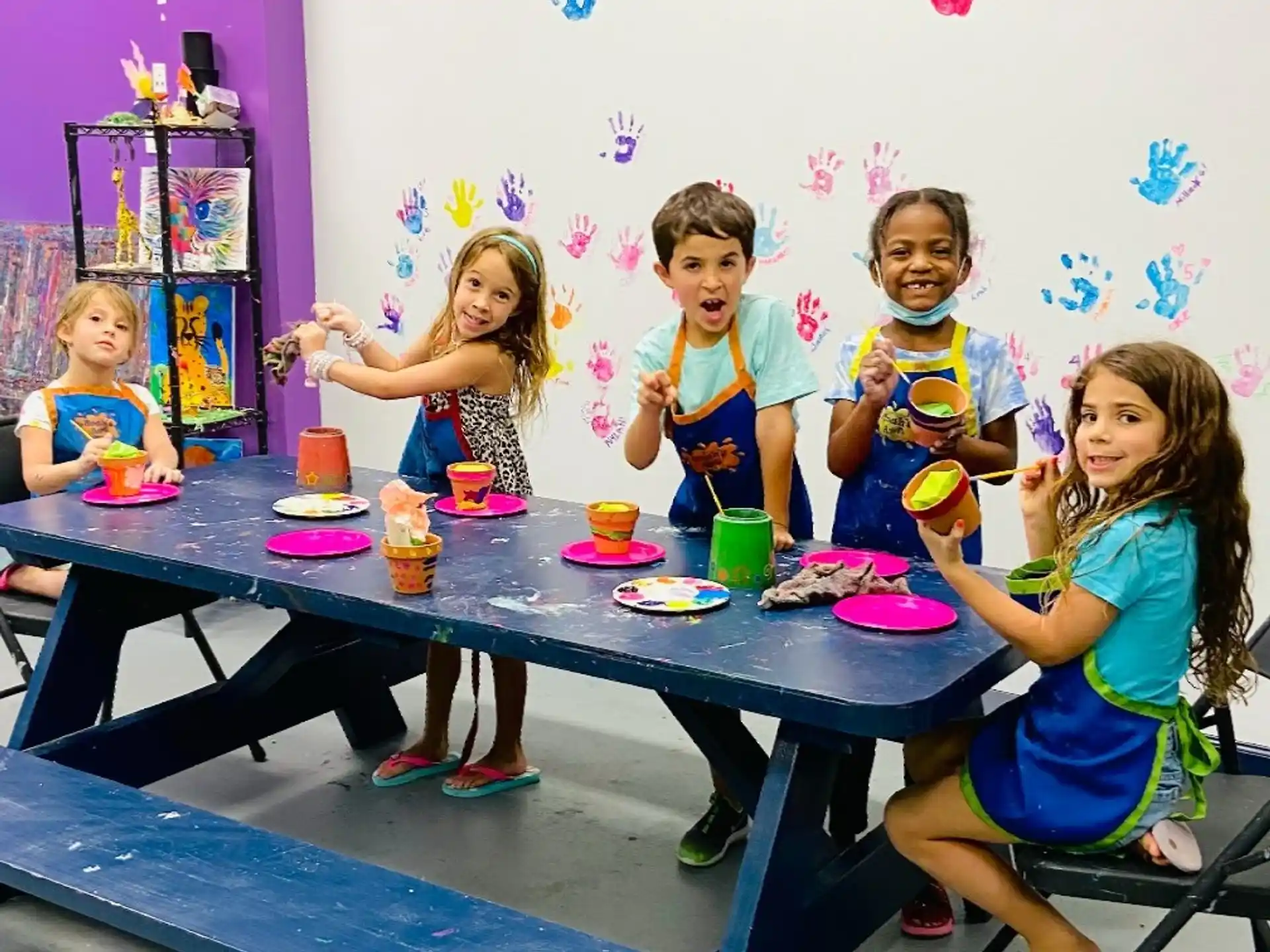 a group of children sitting at a table with food and drinks