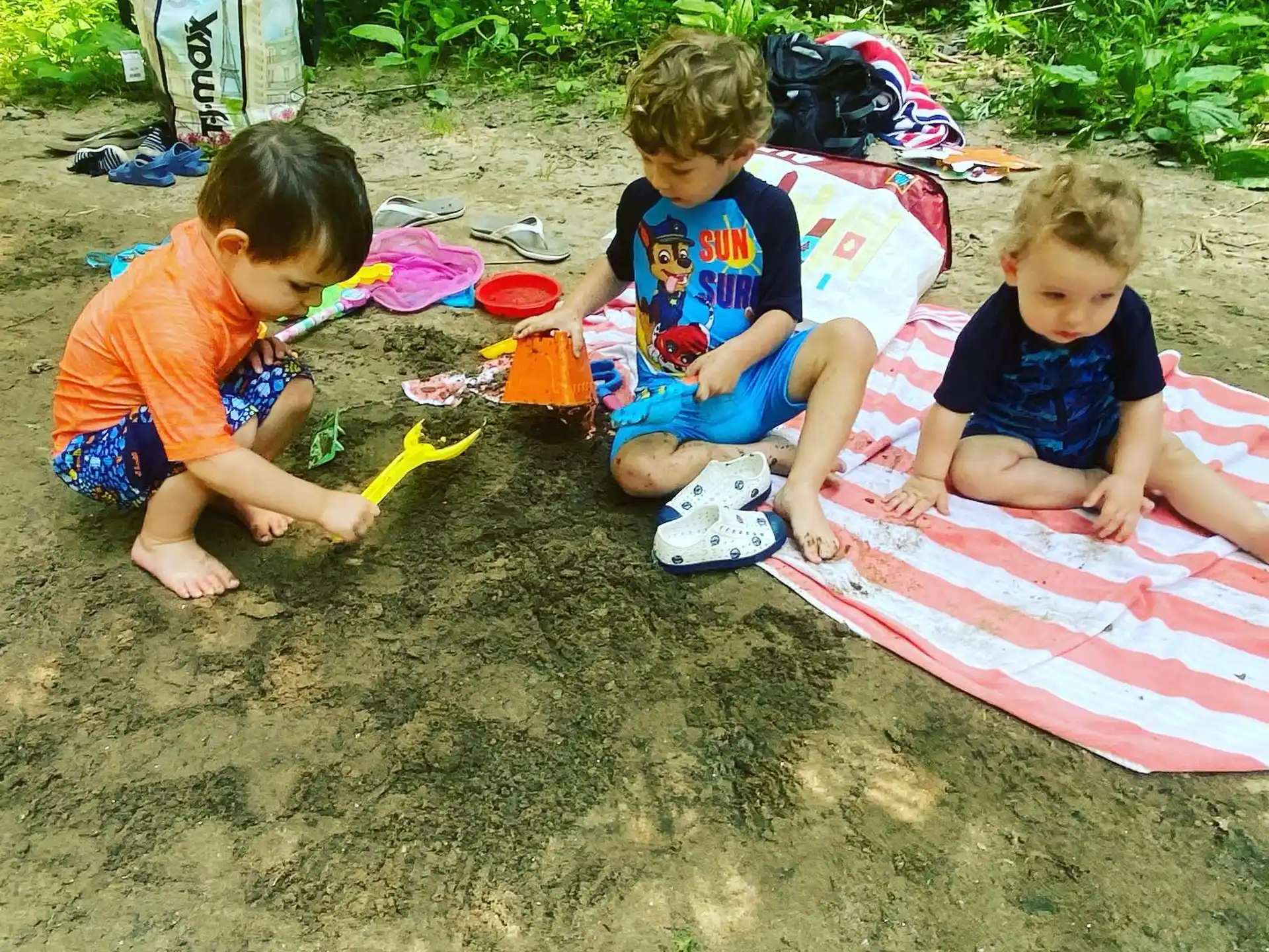 a group of kids playing on a blanket on the sand