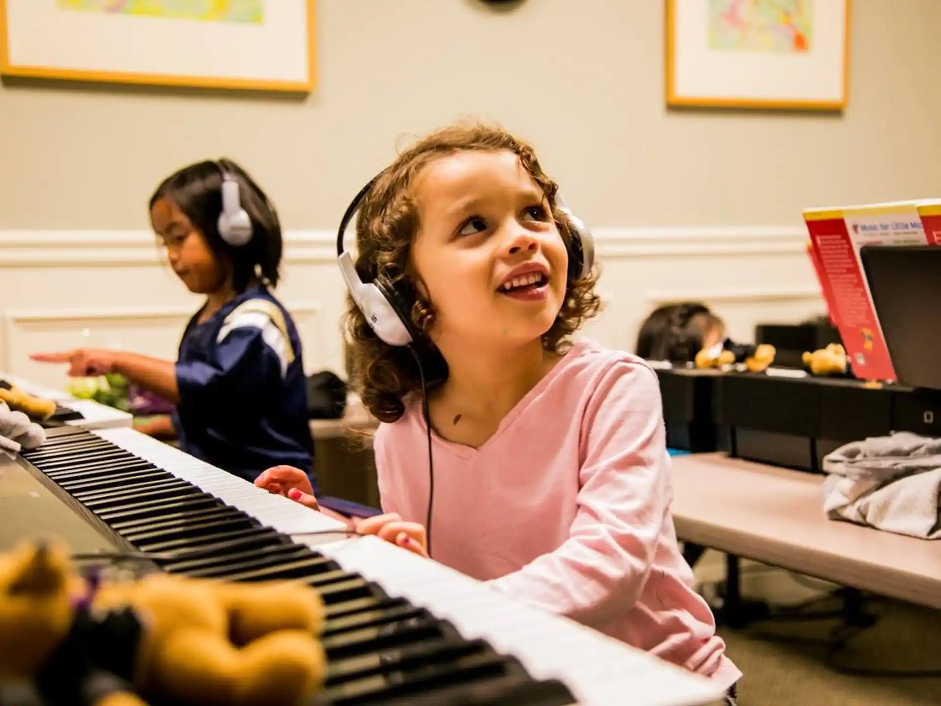 a young girl wearing headphones and playing a piano