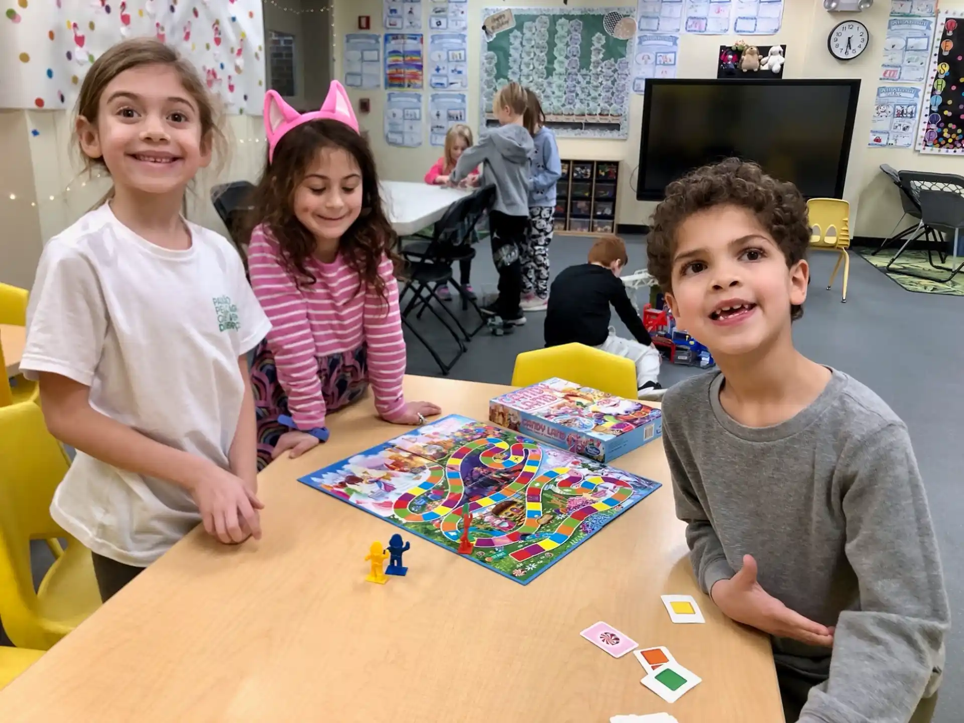 a group of children sitting at a table with a board game