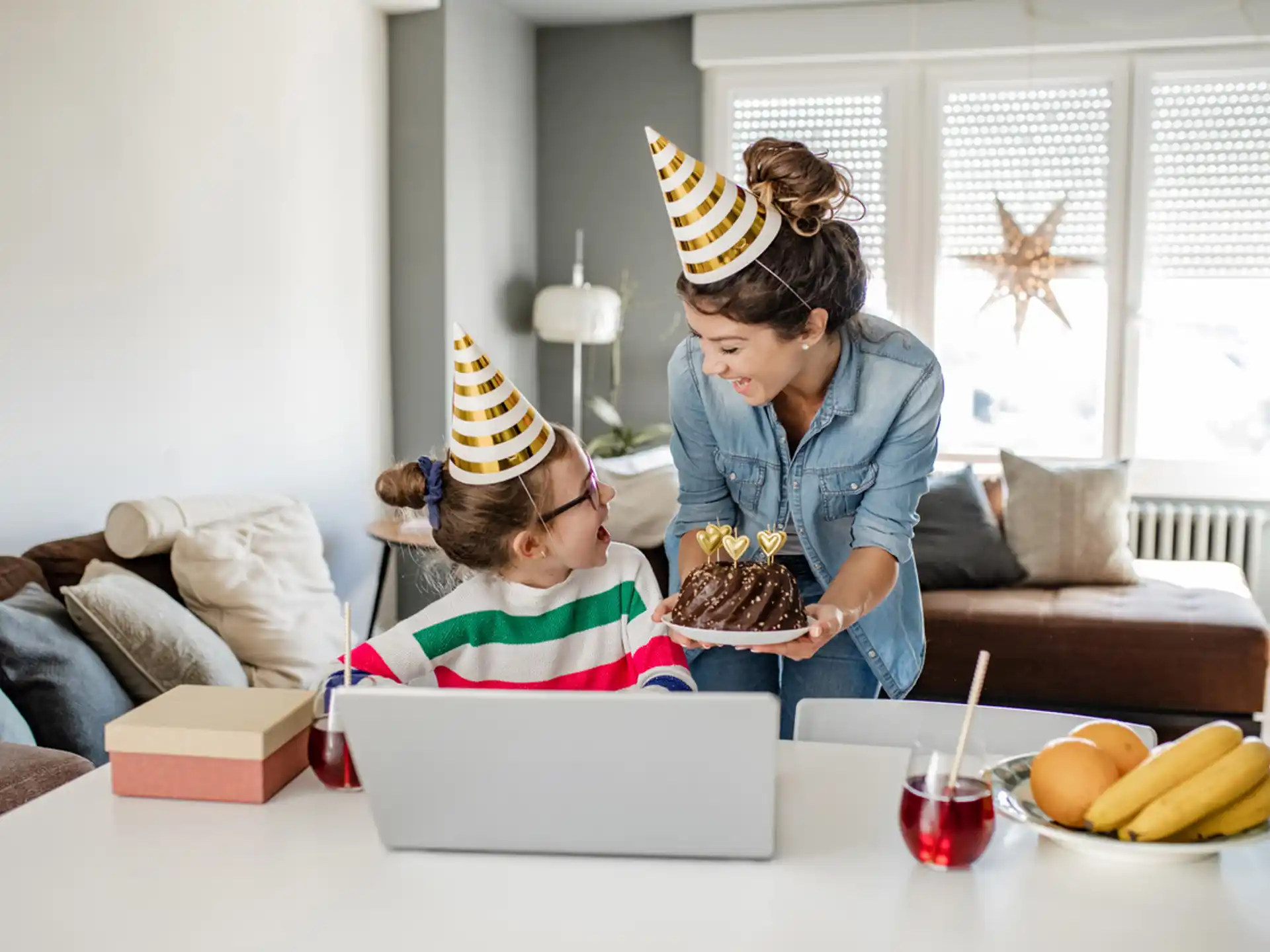 a woman and a child wearing party hats and looking at a laptop