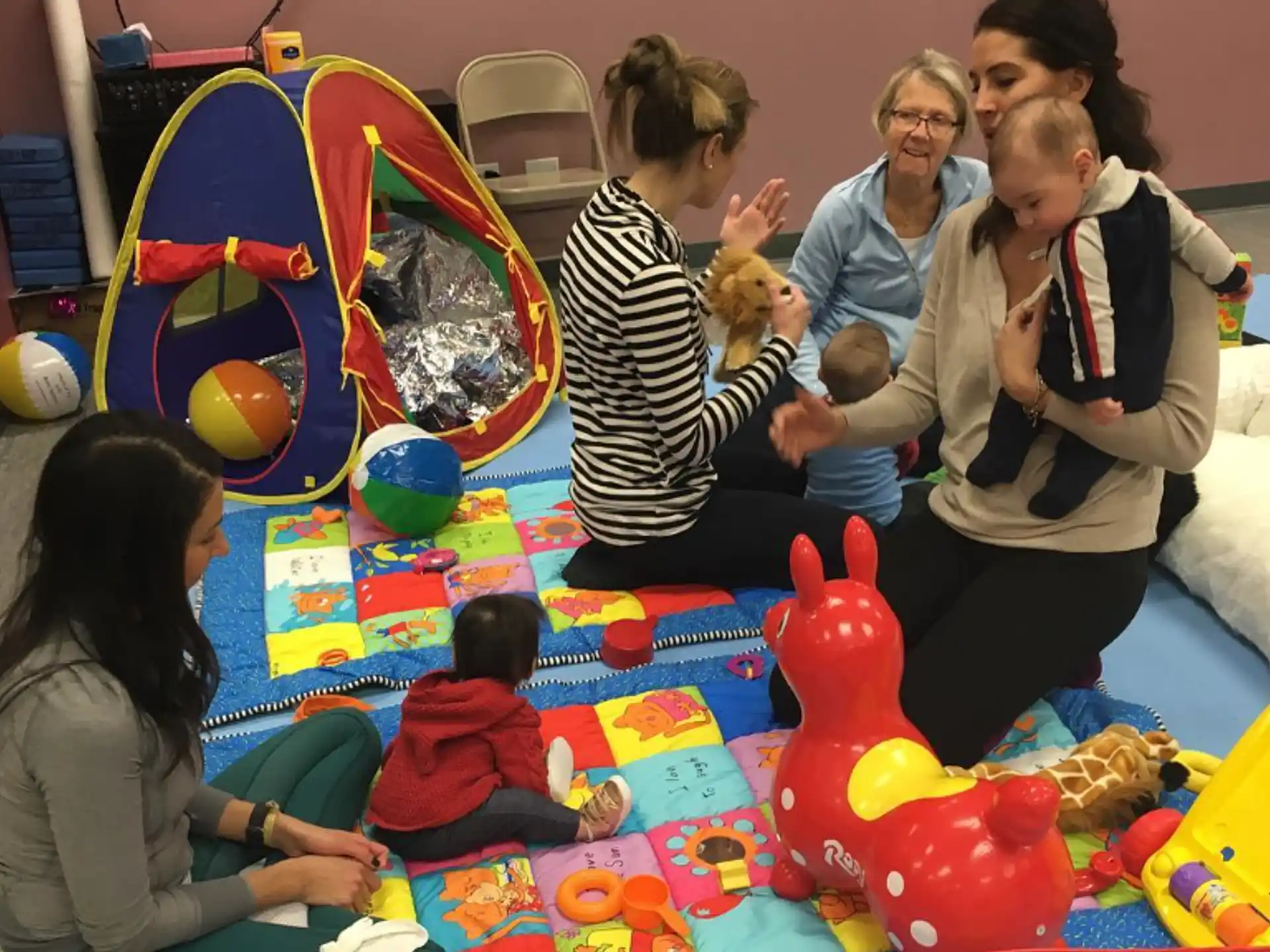 a group of people playing with a baby