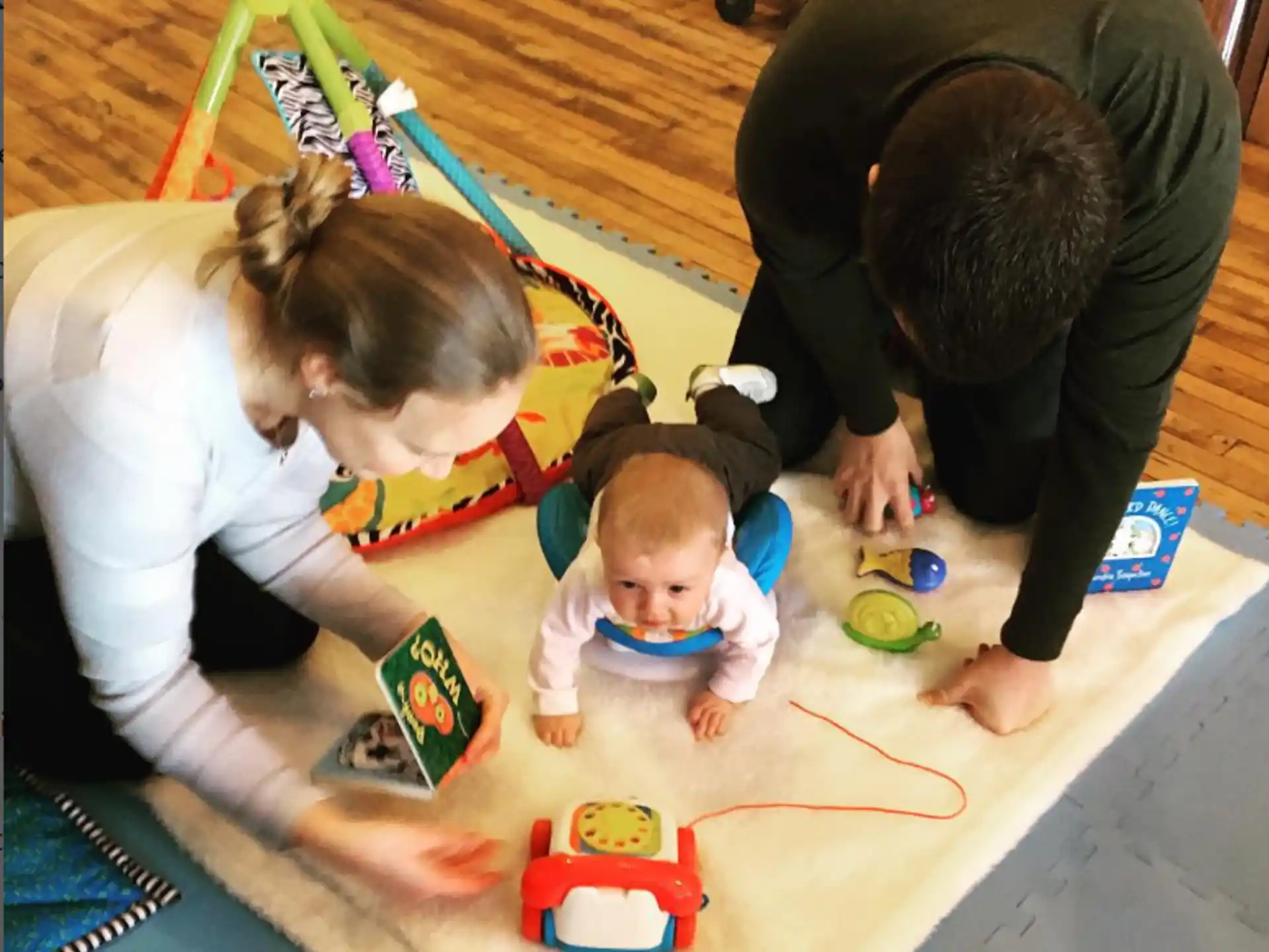 a person and a baby playing with toys on a wood floor